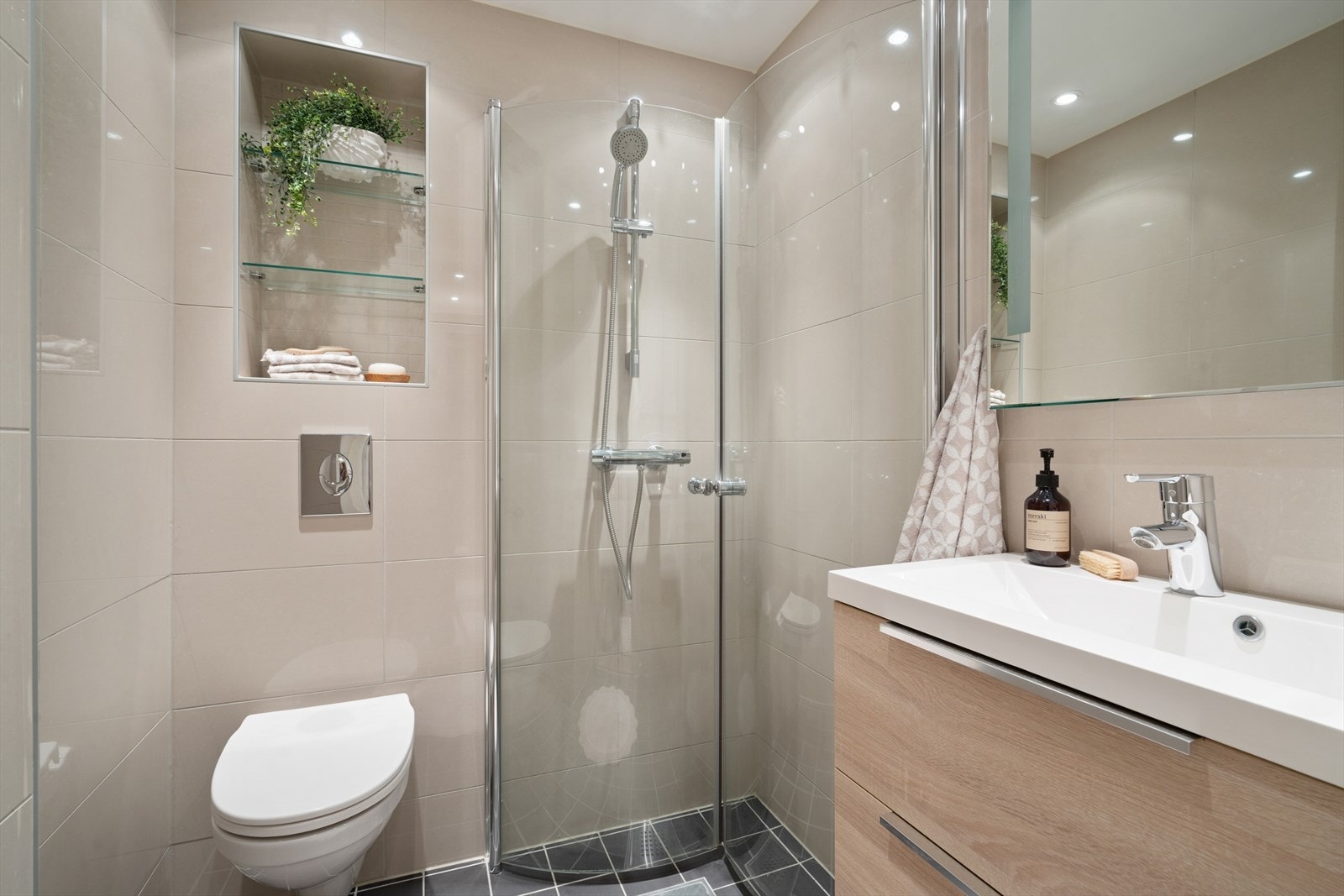 Baderommet er innredet med veggmontert WC, hjørnedusj med dusjvegger og servant med pent underskap. Det er varmekabler i gulvet. Galleribilde