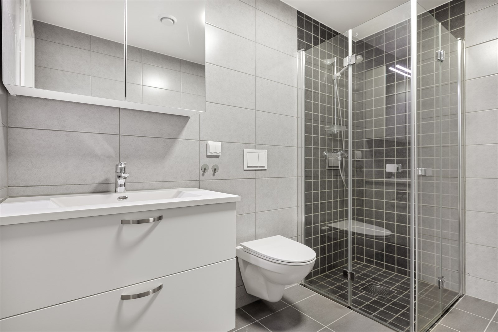 Badet er utstyrt med dusjhjørne med innfellbare dører og innebygd sisterne. Galleribilde