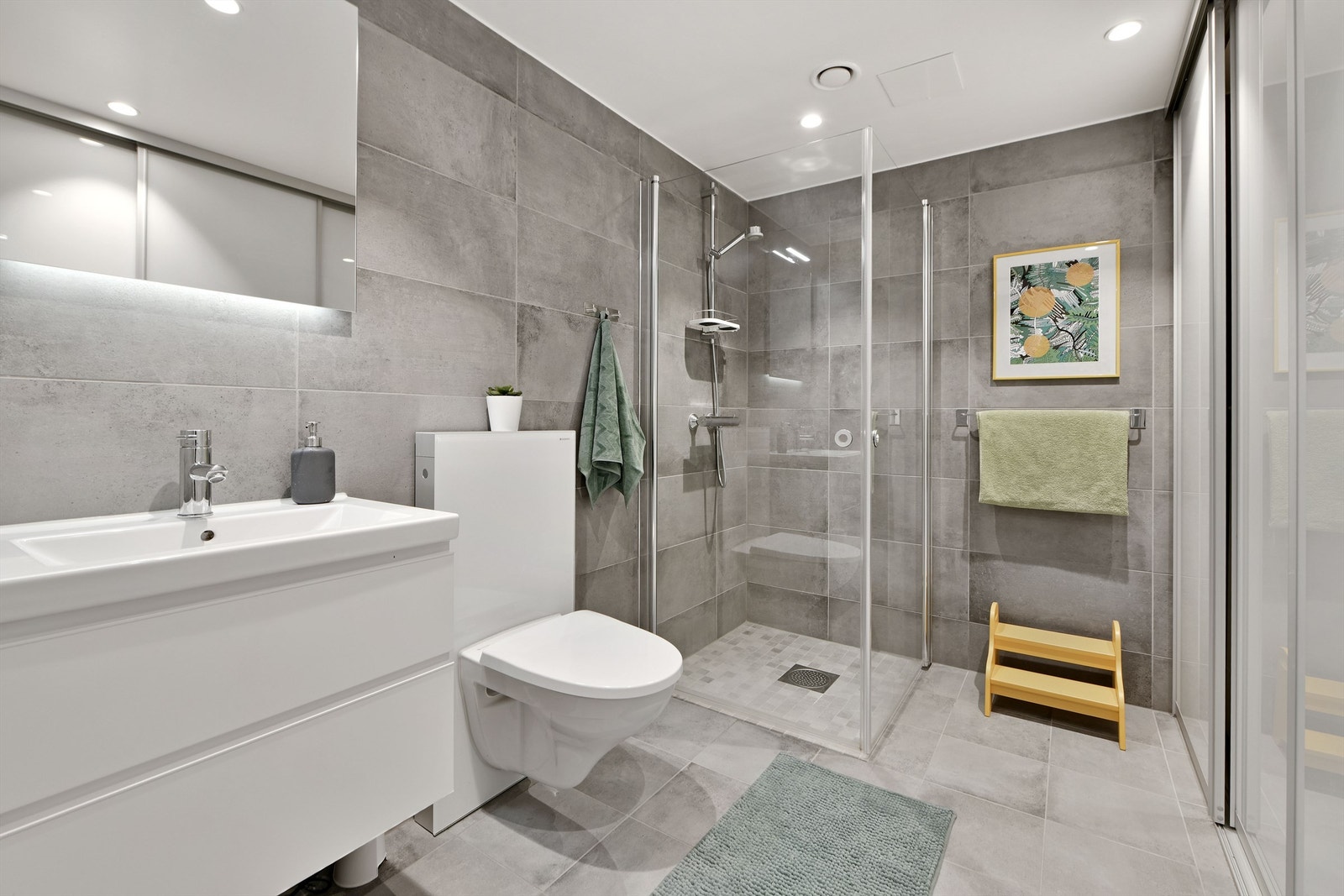 Bad i 1.etg - flislagte gulv og vegger, malt himling - gulvvarme - downlights i himling - baderomsinnredning (servant med underskap og speil over servant - dusjhjørne - skyvedørsløsning ("bak" denne er det skap-og benkeplass, samt opplegg til vaskemaskin) Galleribilde