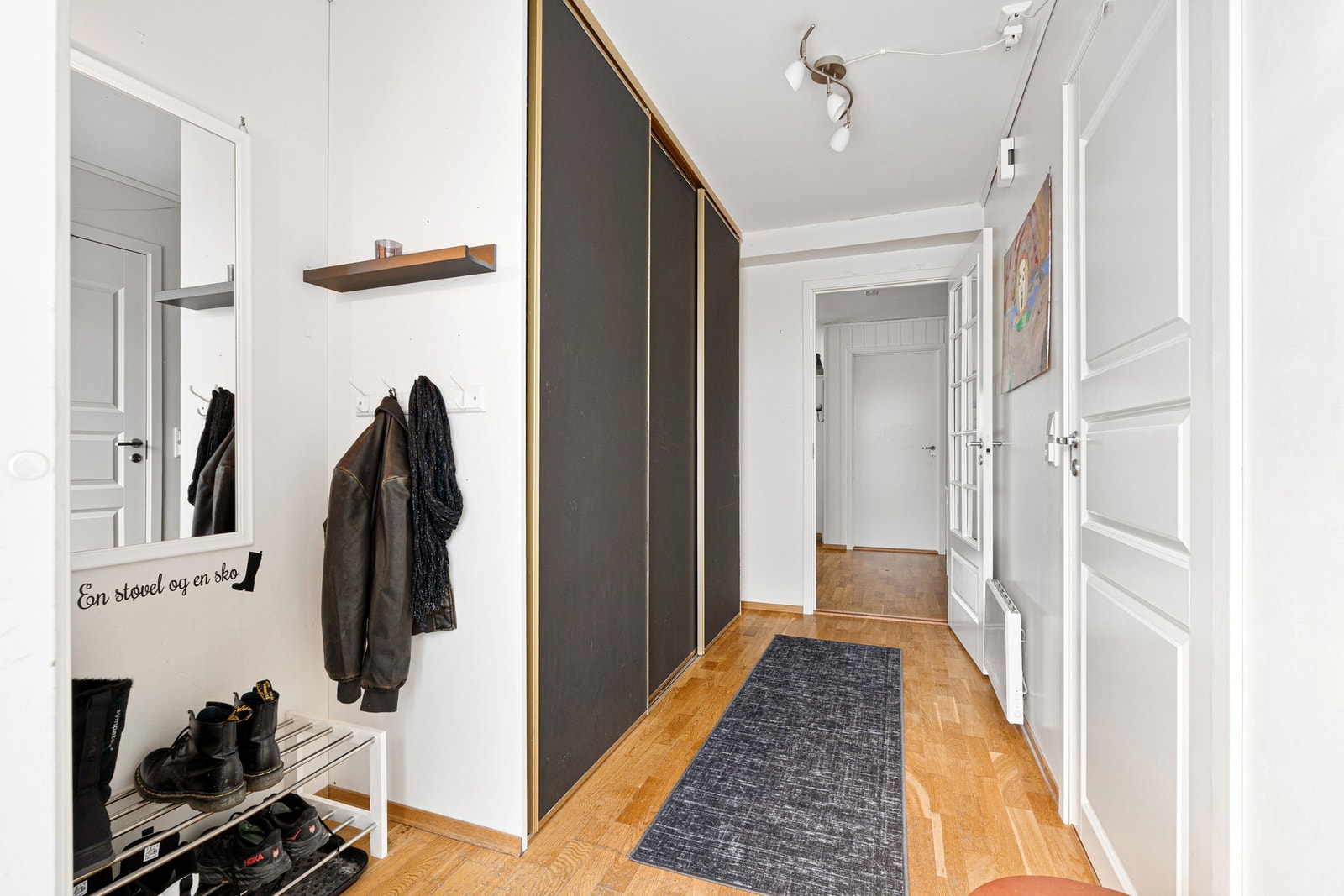 Romslig og innbydende entré med stor skyvedørsgarderobe. Galleribilde
