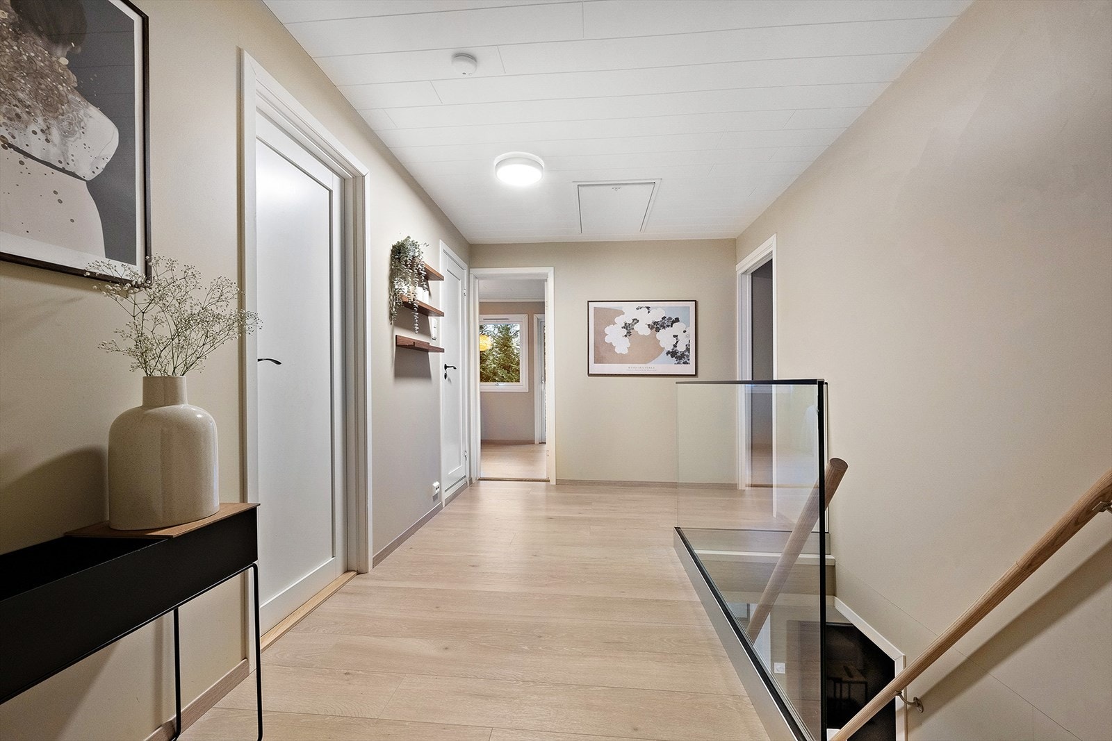 Gangen utenfor kjøkkenet har tilkomst til 2 soverom, ett disponibelt rom og ett bad (uinnredet). Fra gangen er det trapp med glassrekkverk ned til underetasjen. Galleribilde