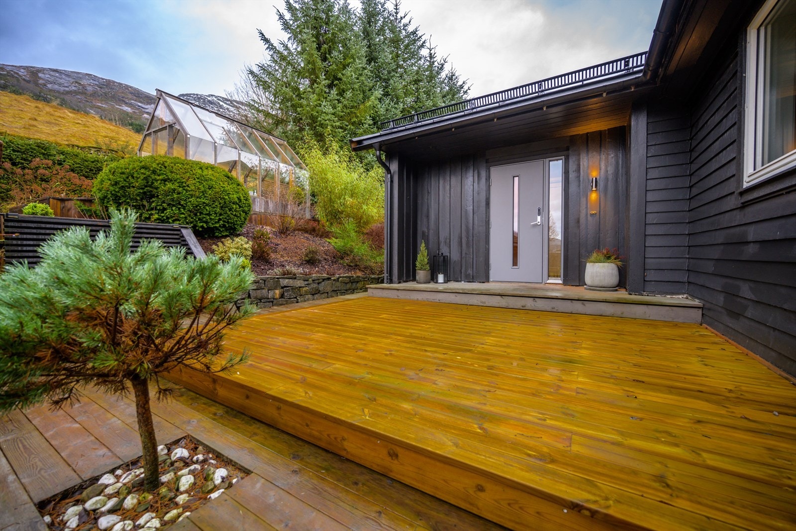 Huset har ett ryddig inngangsparti med terrasse og beplantning. Galleribilde