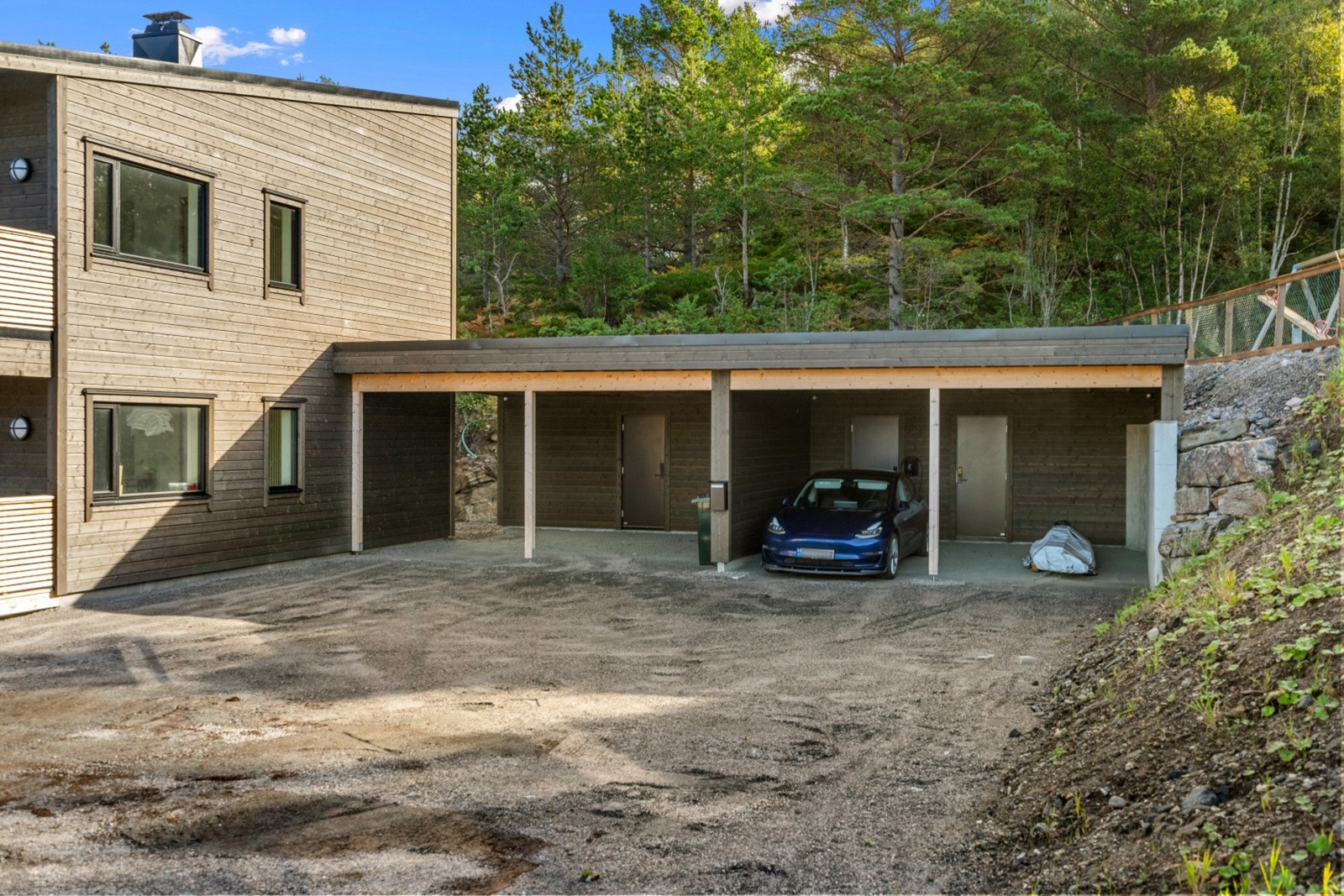 Parkering i carport med ladestasjon for el-bil og sportsbod i bakkant. Galleribilde