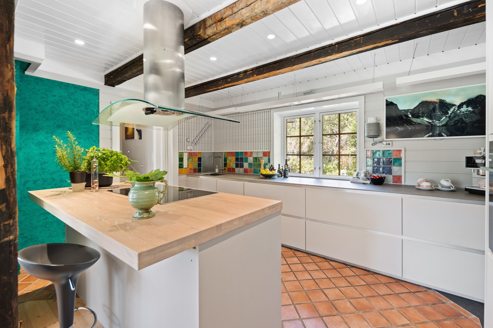 Moderne kjøkkeninnredning med hvite, slette fronter og kjøkkenøy med praktisk barløsning. Galleribilde