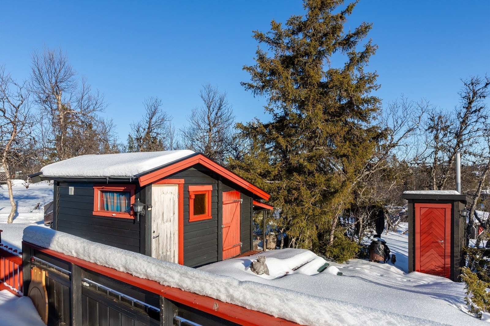 Fra terrassen på baksiden går det trapp ned til ny platting og et enkelt uthus med to boder. I tillegg har eiendommen en enkel uisolert utedo med dobenk av tre. Galleribilde