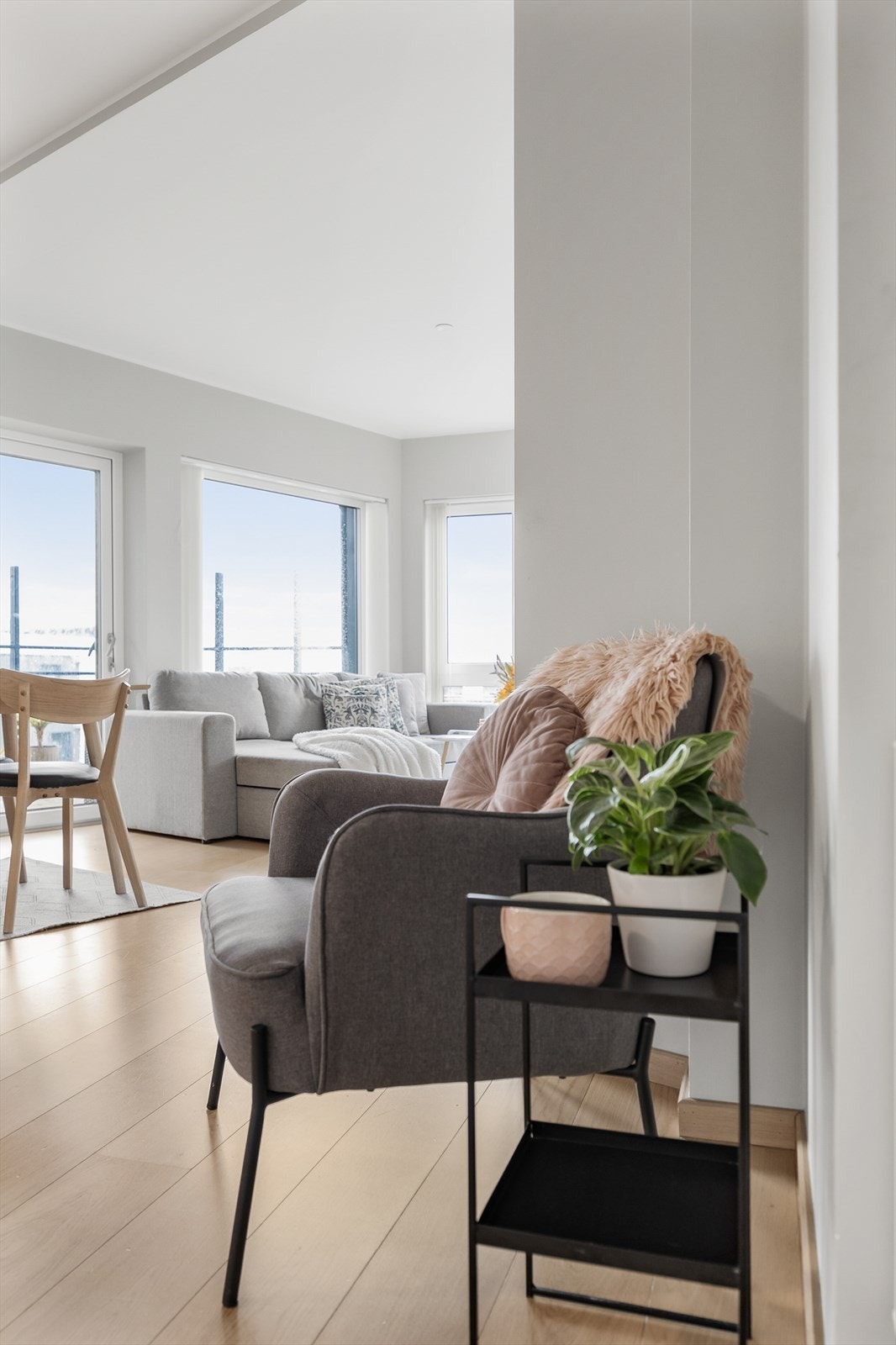 Åpen stue- og kjøkkenløsning med gjennomgående parkett og lyse vegger. Galleribilde