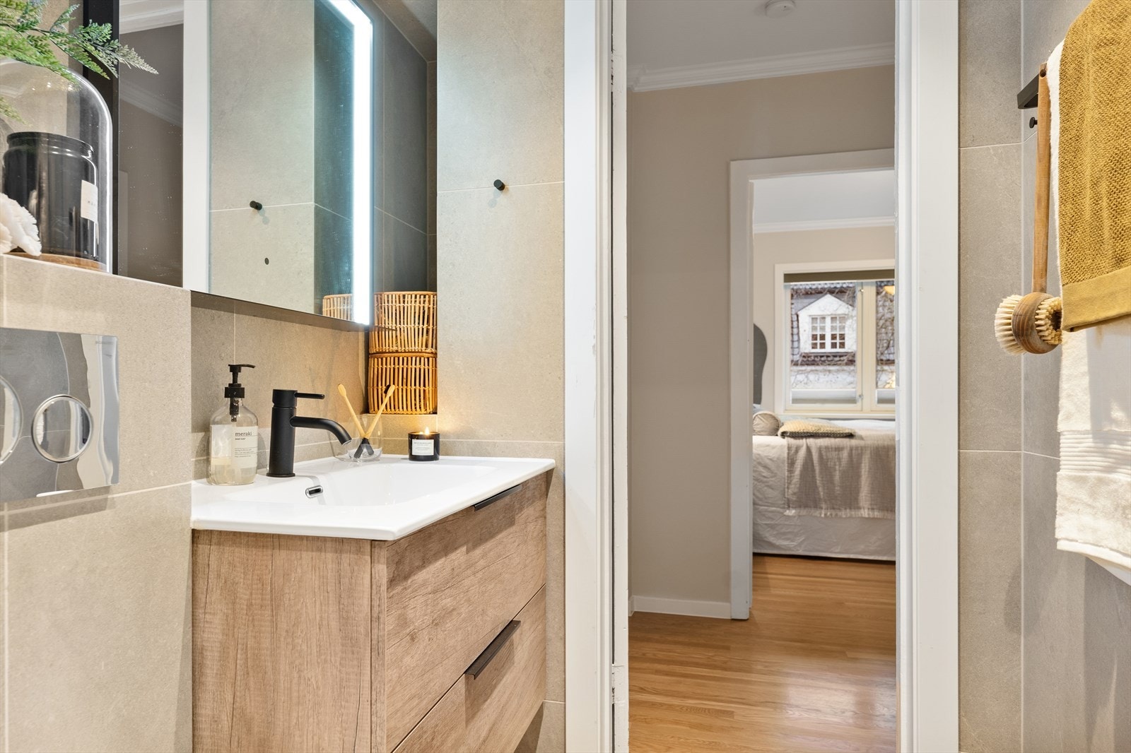 Badet er innredet med dusj på gulv med dør i herdet glass, veggfestet klosett, servant i helstøpt plate, benkeskap med glatte fronter og speil over servant. Galleribilde