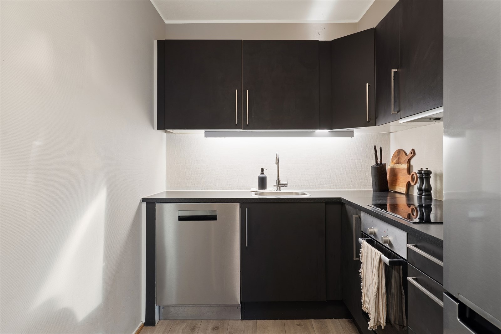 Kjøkkeninnredningen har glatte fronter, laminatbenkeplate og integrerte hvitevarer. Galleribilde