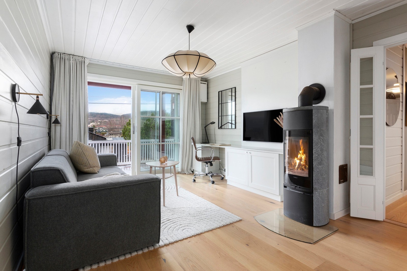 Lys og lun stue med klebersteinsovn, god plass til sofagruppe og direkte utgang til terrassen på 75 kvm - et perfekt rom for både store og små. Galleribilde