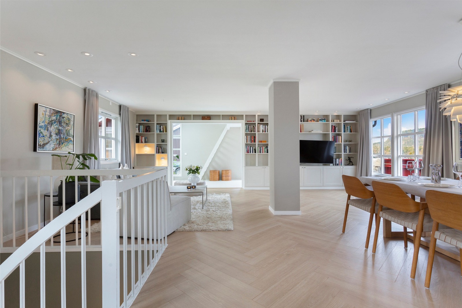 Lys og romslig stue med vakker fiskebensparkett fra 2024, store vindusflater og plassbygde bokhylle - et elegant og sosialt samlingspunkt i hjemmet. Galleribilde