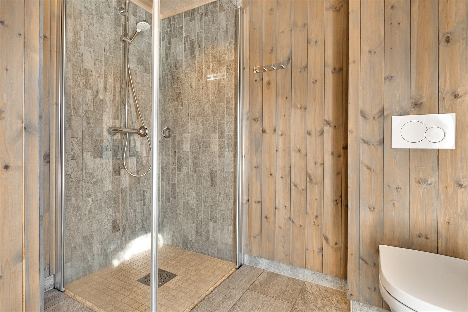 Badet har flislagt gulv med varmekabler, og flislagte dusjhjørne i nedsenket dusjsone. Galleribilde