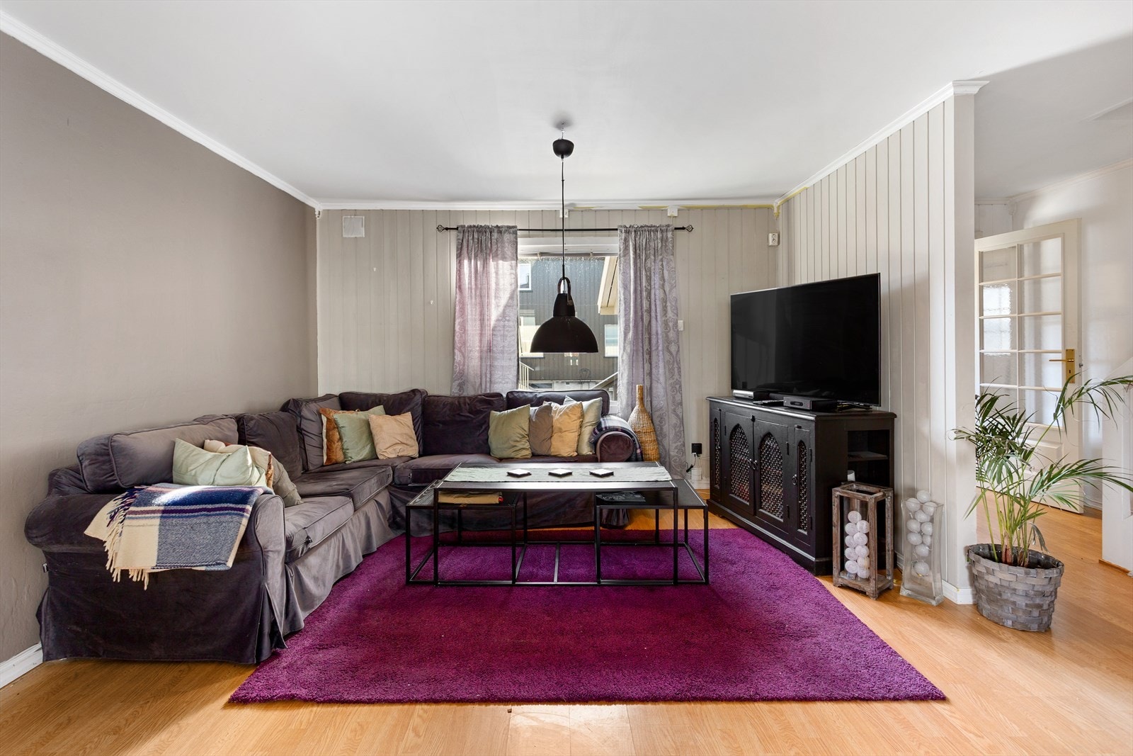 Stue med laminat på gulv og malt panel og tapet. Galleribilde