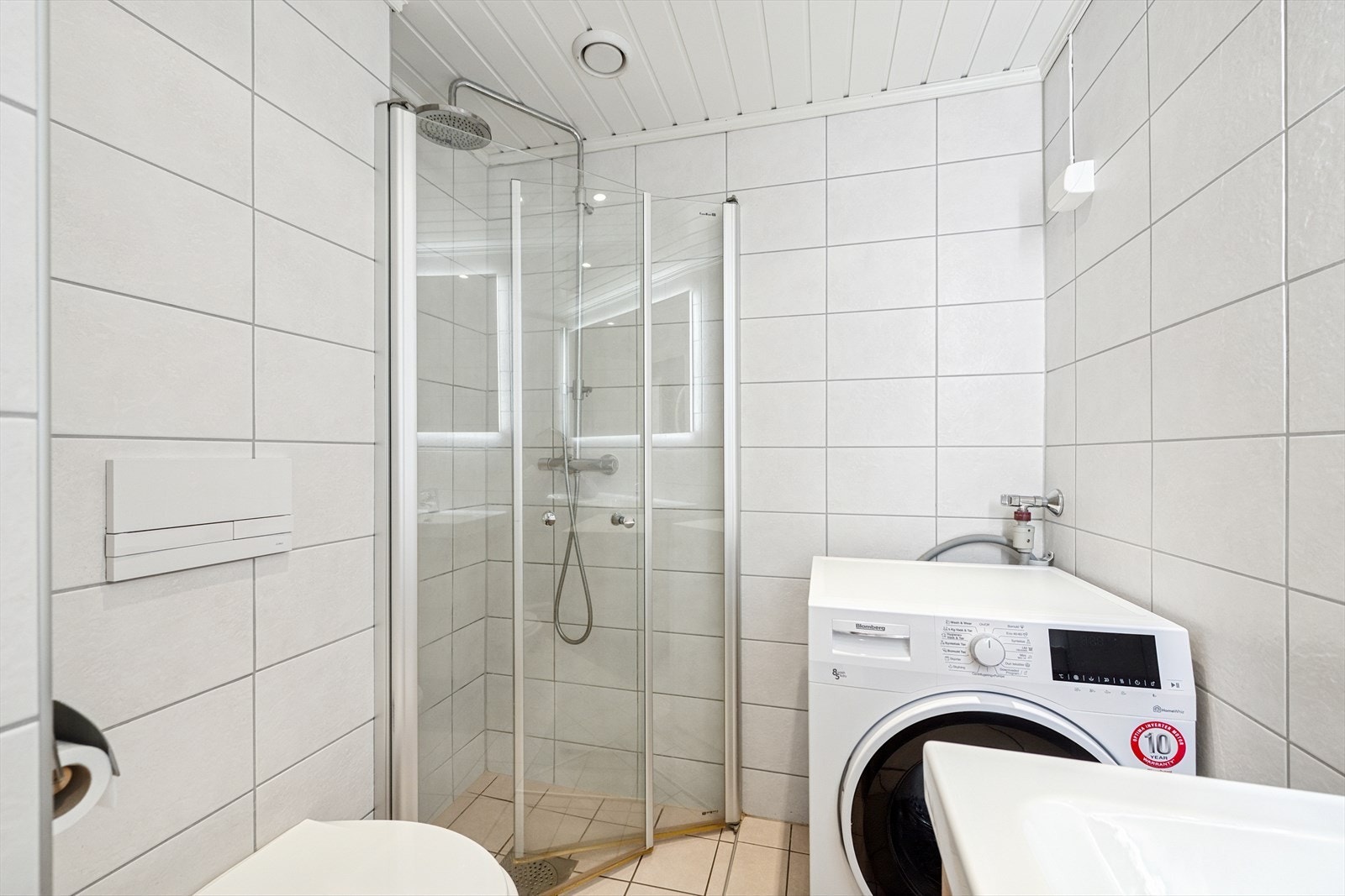 Badet er innredet med baderomsinnredning med dobbel servant, underskap, vegghengt toalett, dusjvegger og opplegg til vaskemaskin Galleribilde