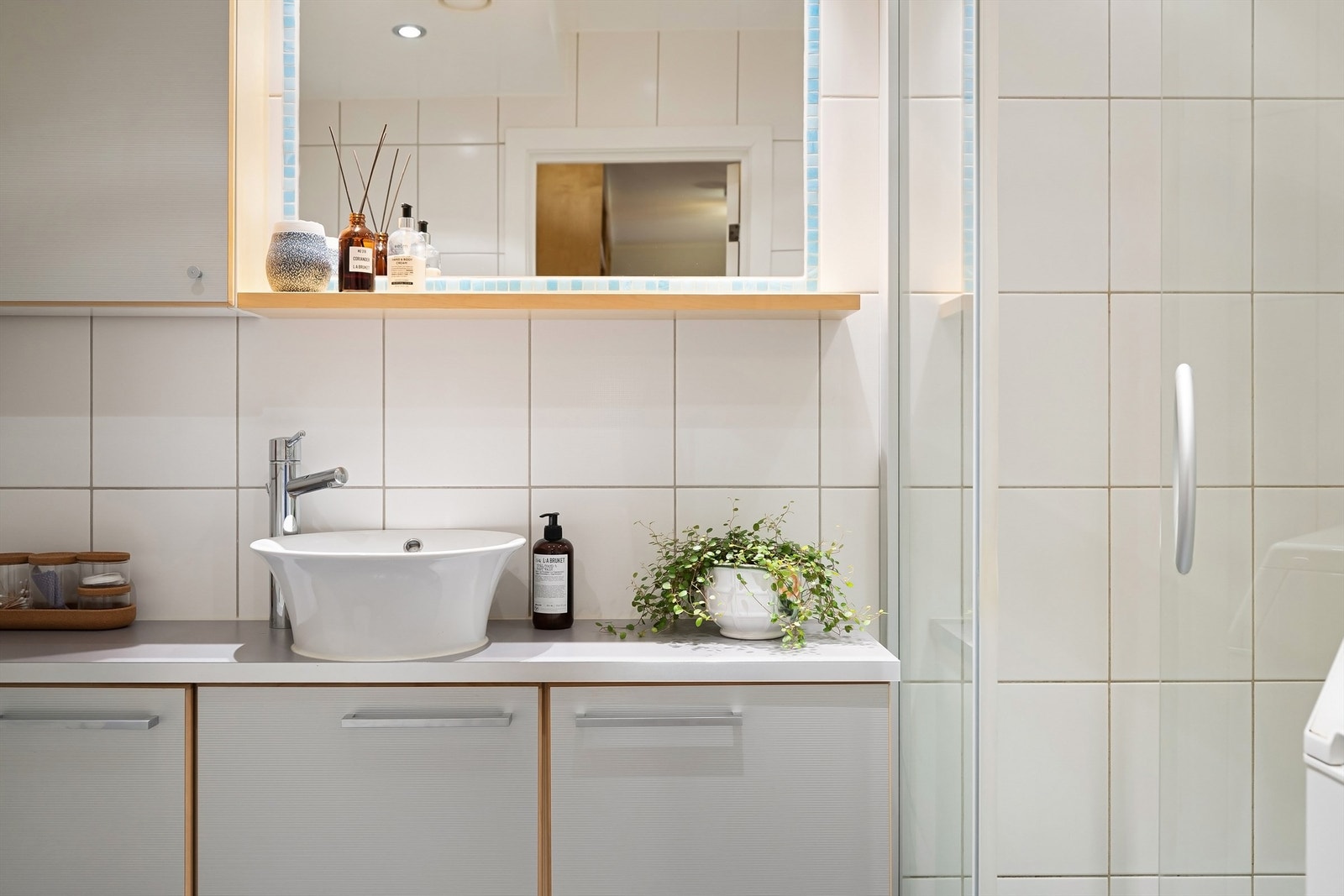 Innredning med en heldekkende skapinnredning fra HTH med ovenpåliggende servant og speil med belysning og skap på vegg over Galleribilde