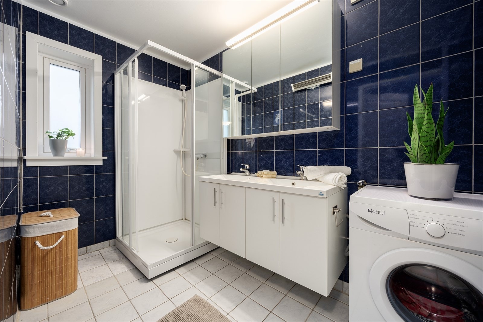 Romslig baderom med innredning bestående av bl.a. servantskap med glatte, folierte fronter og heldekkende servant, dusjkabinett og opplegg for vaskemaskin. Våtrommet må oppgraderes for å tåle normal bruk etter dagens krav. Galleribilde