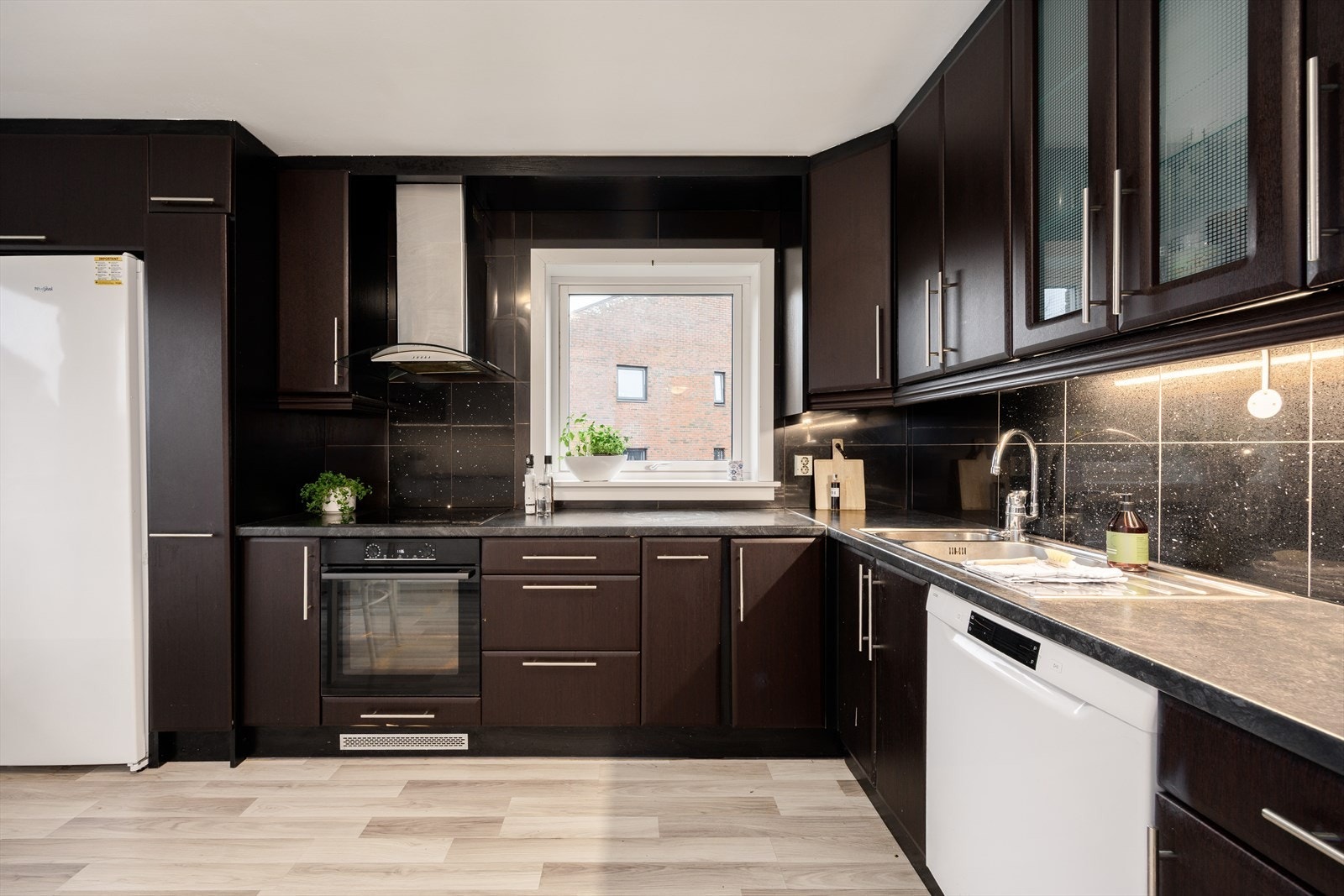 Kjøkkeninnredning bestående av bl.a. integrert platetopp, stekeovn, mikro, fryseskap, oppvaskmaskin i nisje og frittstående kjøleskap. Galleribilde