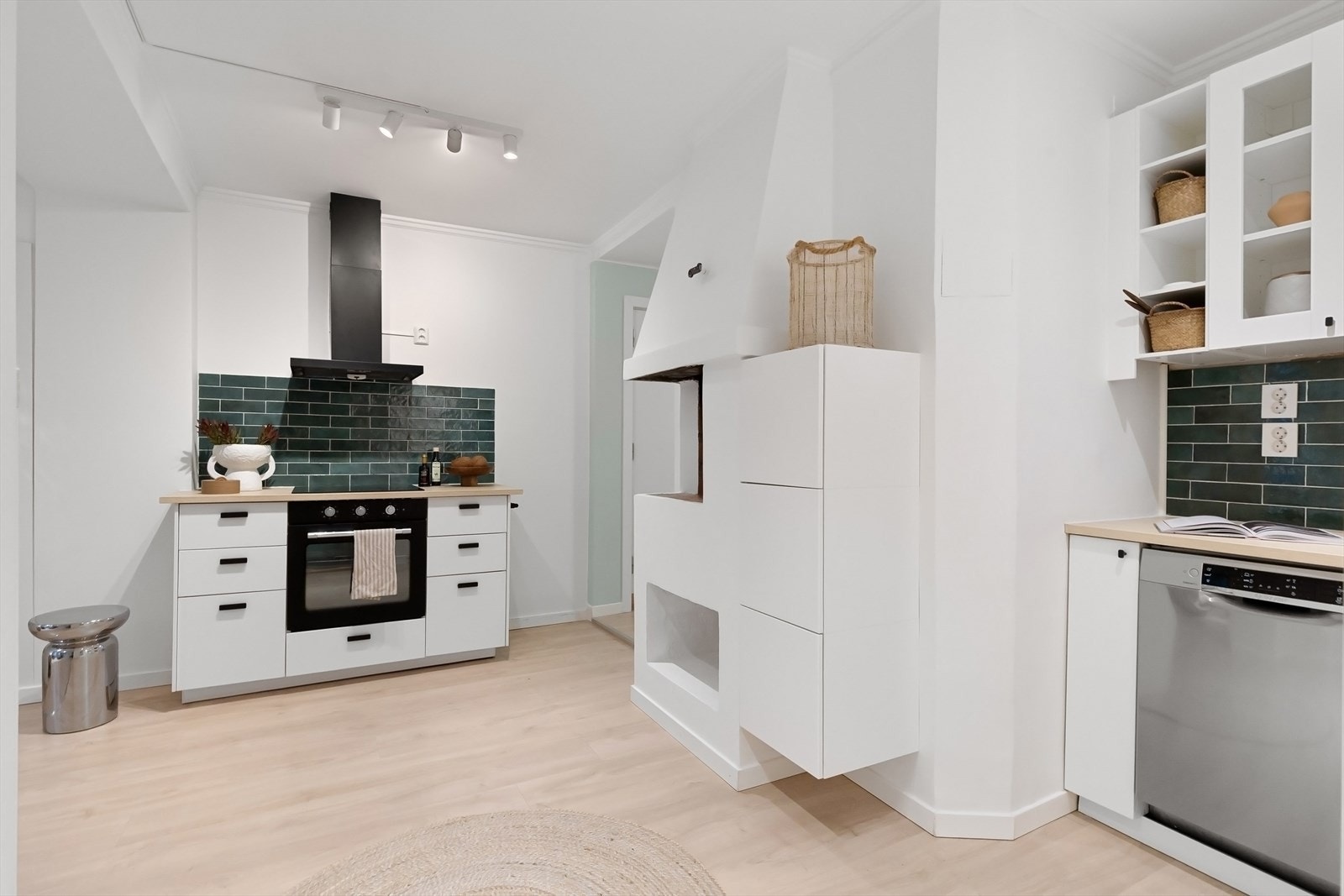 Lys innredning med glatte fronter, enkelte fronter med glass, fliser på vegg over kjøkkenbenken og benkeplate i laminat. Galleribilde