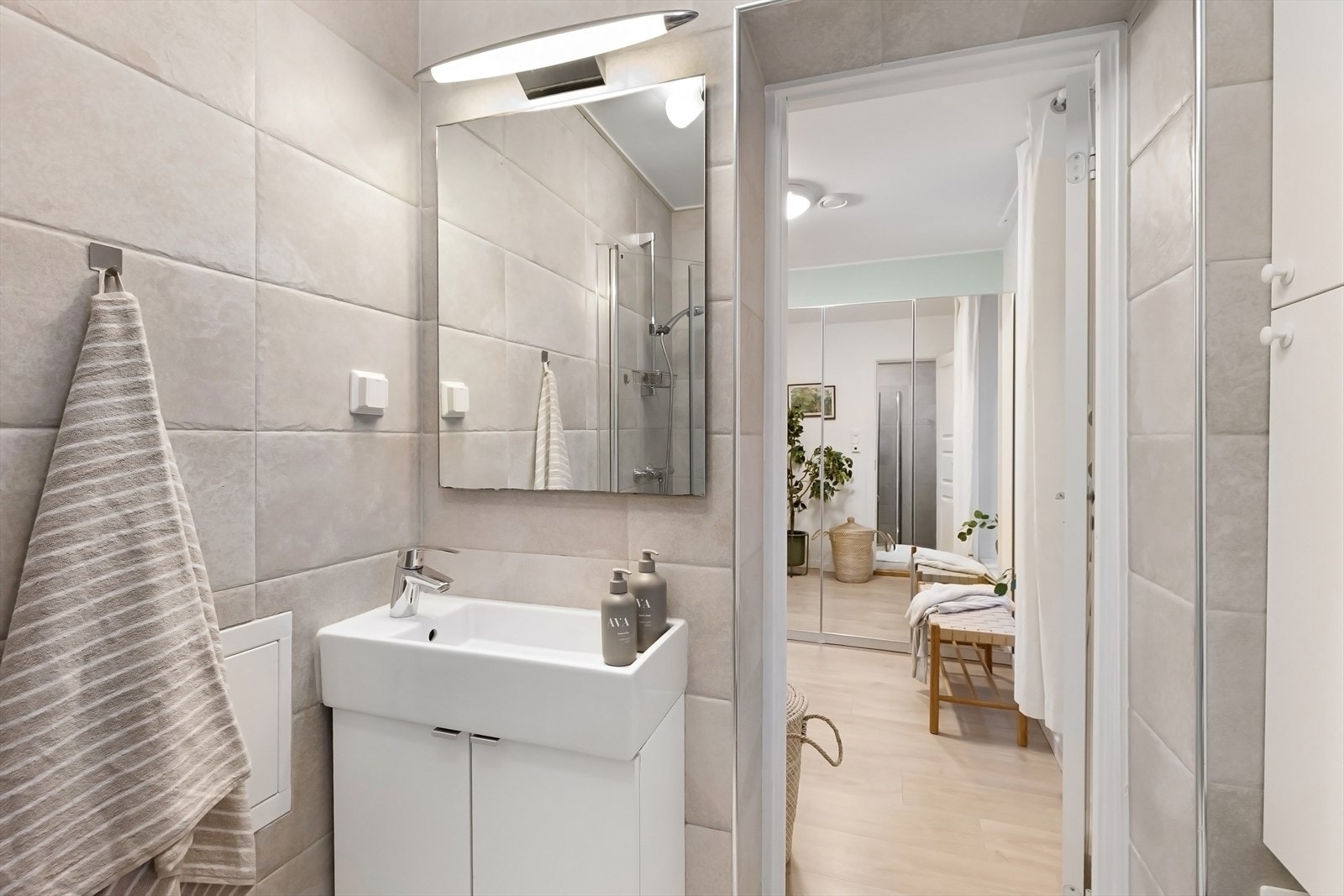 Badet er utstyrt med dusjhjørne med innfellbare dusjdører og blandebatteri, veggmontert toalett og baderomsinnredning med skuffer, hvit servant med blandebatteri. Galleribilde