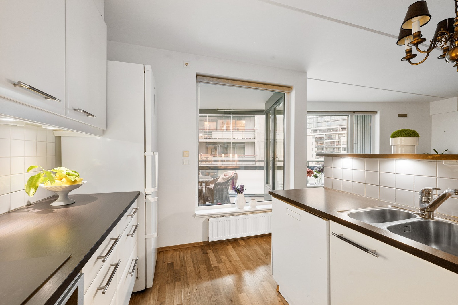 Benkeplaten i laminat er praktisk utformet med nedfelt oppvaskkum i rustfritt stål, og det er fliser på vegg over benkeplate som gir et lettstelt og funksjonelt arbeidsområde. Galleribilde