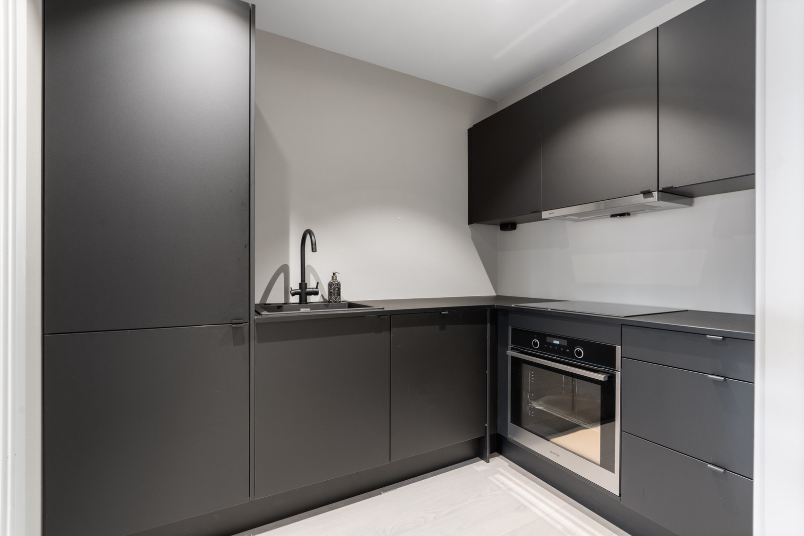 Moderne kjøkken i mørk farge som skaper kontrast fra de lyse veggene. Hvitevarer følger med. Galleribilde