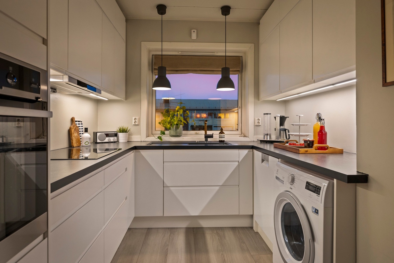 Leiligheten har et moderne og stort kjøkken med hvite fronter Galleribilde