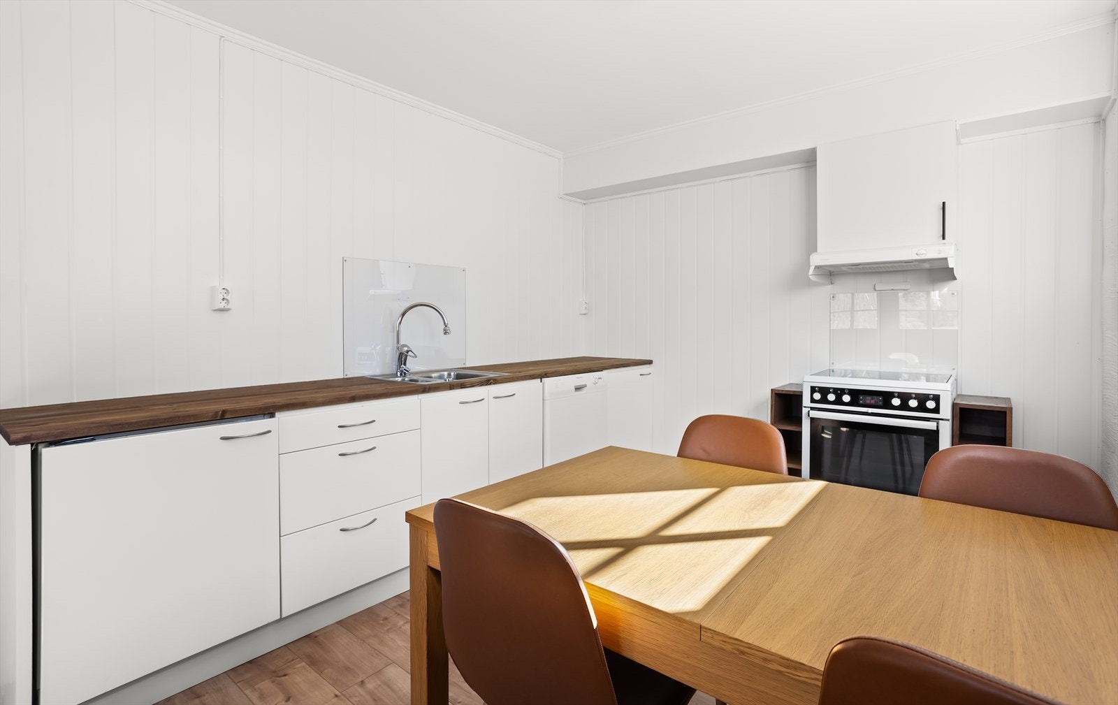 Flott, hvit kjøkkeninnredning med mørk benkeplate. Galleribilde