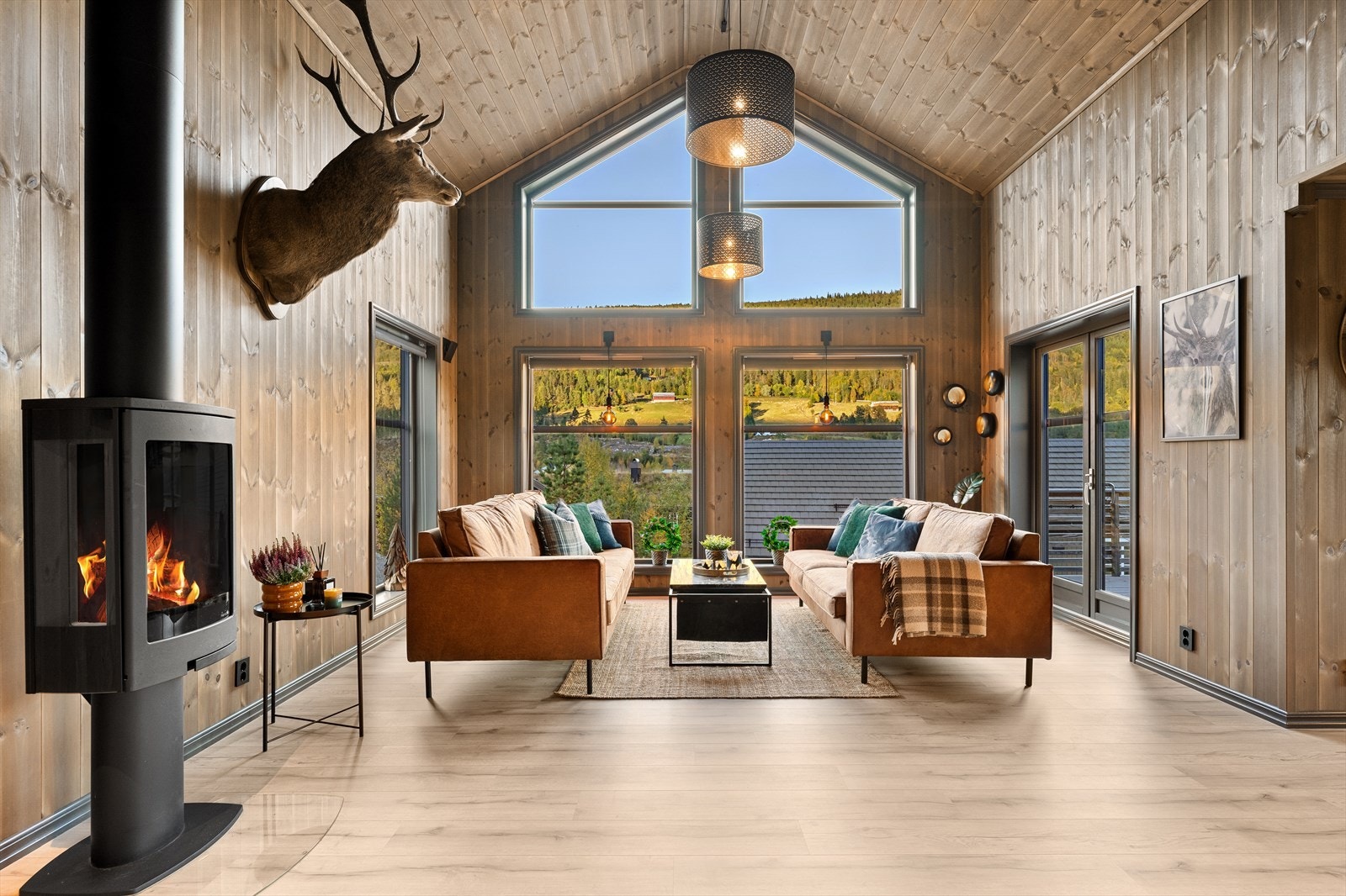 Elegant stue med imponerende vindusflater fra gulv til tak - her strømmer lyset inn og naturen blir en del av interiøret. Galleribilde