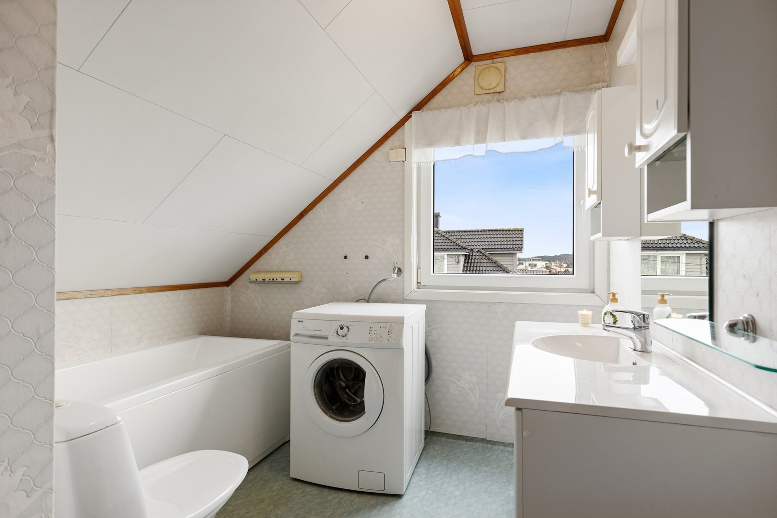 Bad/vaskerom - Eldre våtrom. Veggene har våtromstapet/belegg. Taket har himlingsplater. Gulvet har vinylbelegg. Stråleovn på dette våtrommet. Rommet har badekar, toalett, vask og opplegg for vaskemaskin. Naturlig ventilering. Galleribilde