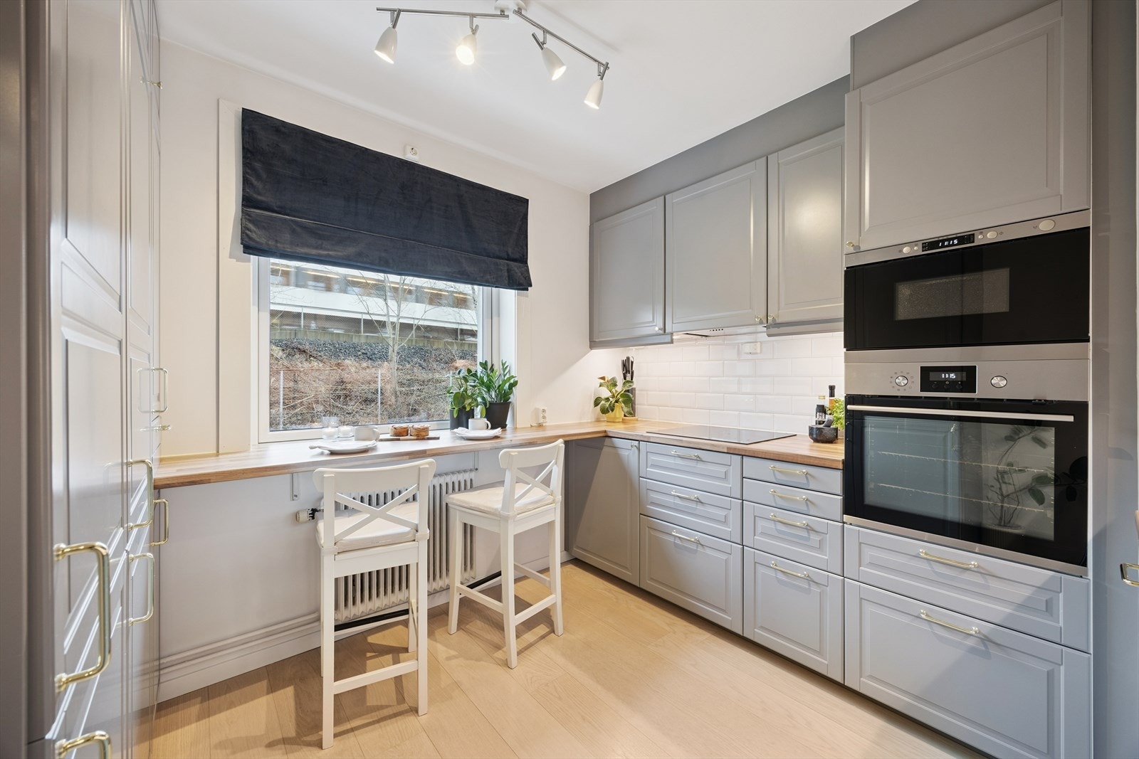 Stilrent kjøkken med integrerte hvitevarer og en praktisk barløsning ved vinduet. Galleribilde