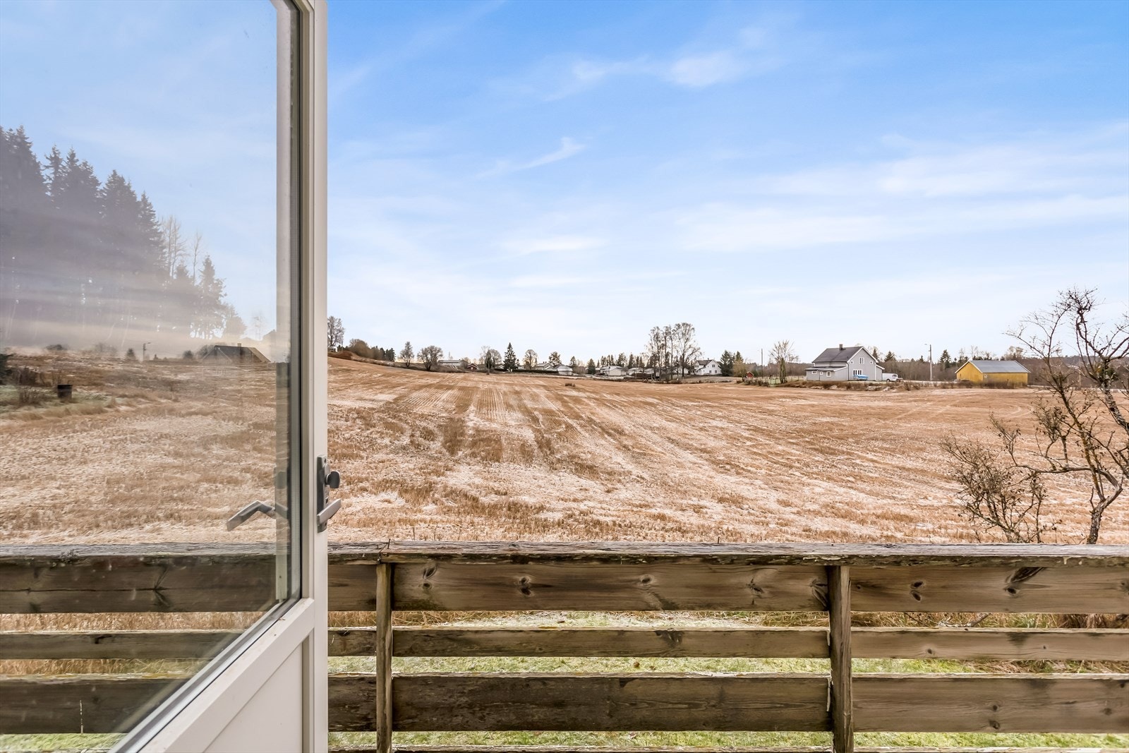 Fra verandaen har man åpen utsikt over jorder og spredt bebyggelse. Galleribilde