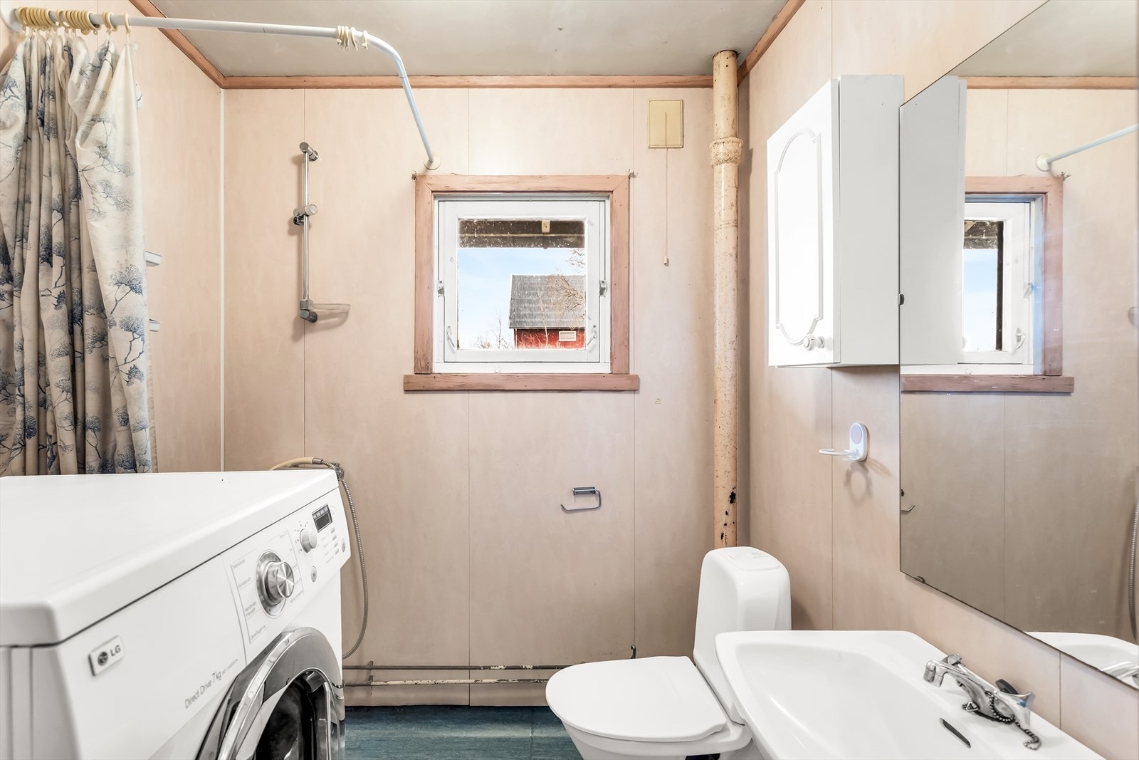 Bad med servant med underskap, speil, dusj med forheng, gulvmontert toalett og opplegg til vaskemaskin. Galleribilde