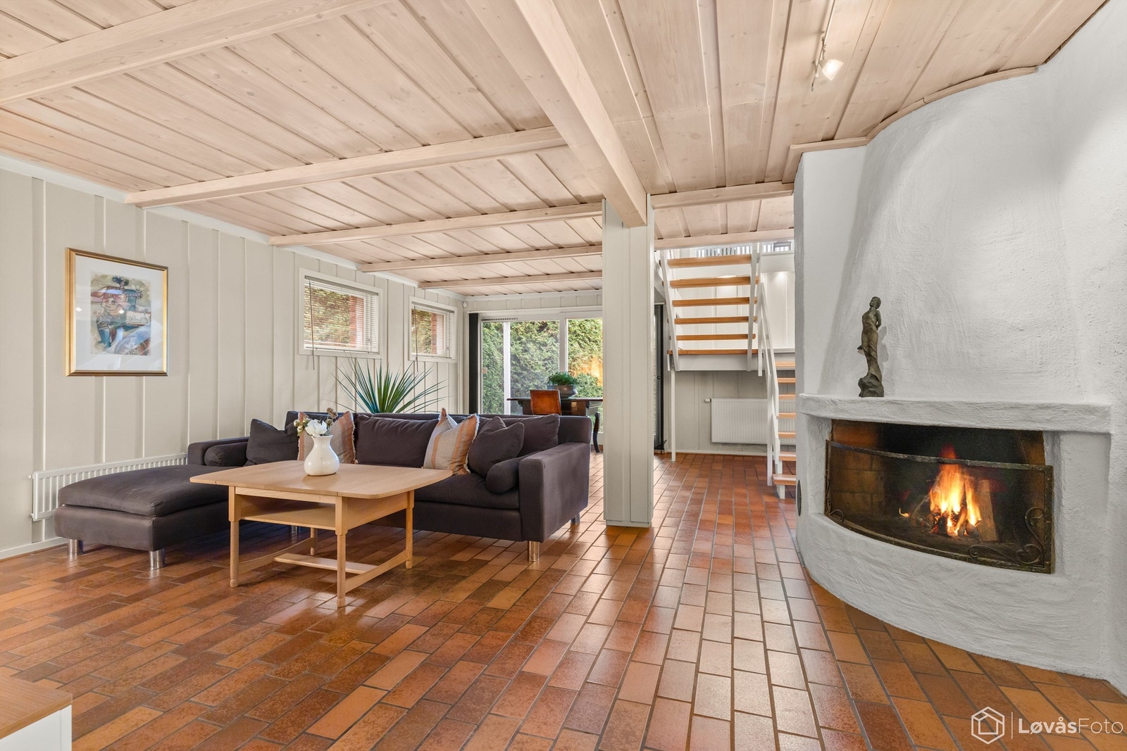 Stor peisestue med peis og skyvedør ut til hagen. Flislagt gulv med vannbåren gulvvarme Galleribilde