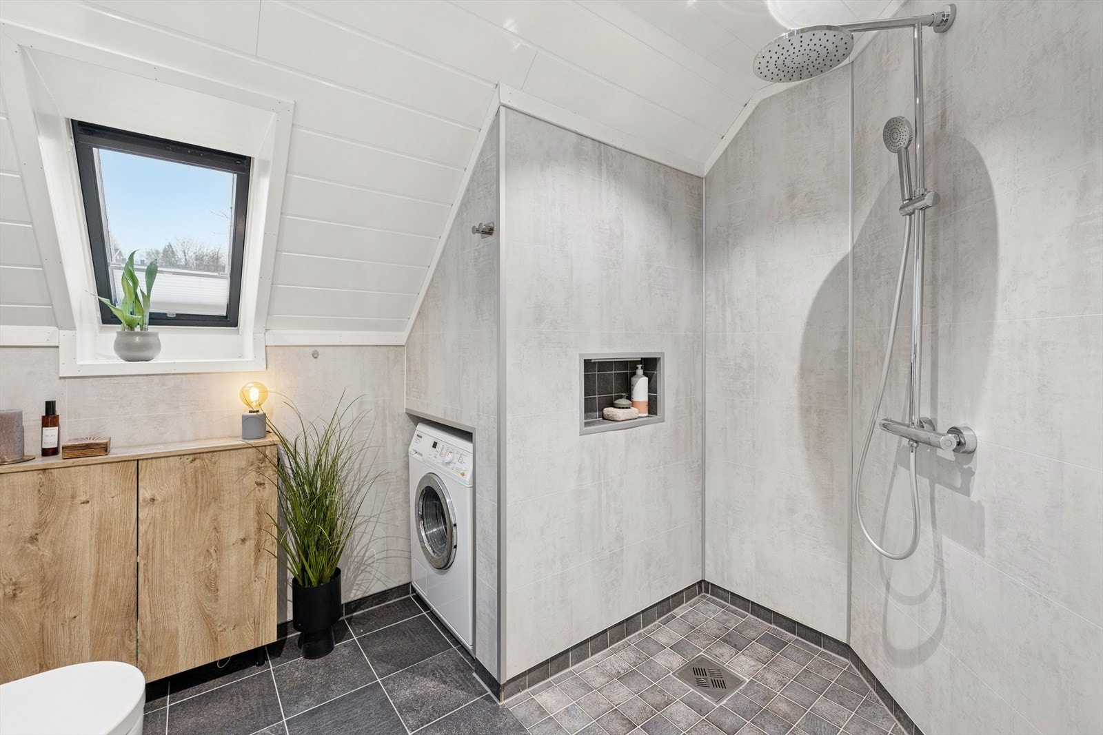 Badet er innredet med servant med underskap, speil med tilhørende belysning. Dusjnisje, vegghengt wc og opplegg for vaskemaskin. Galleribilde