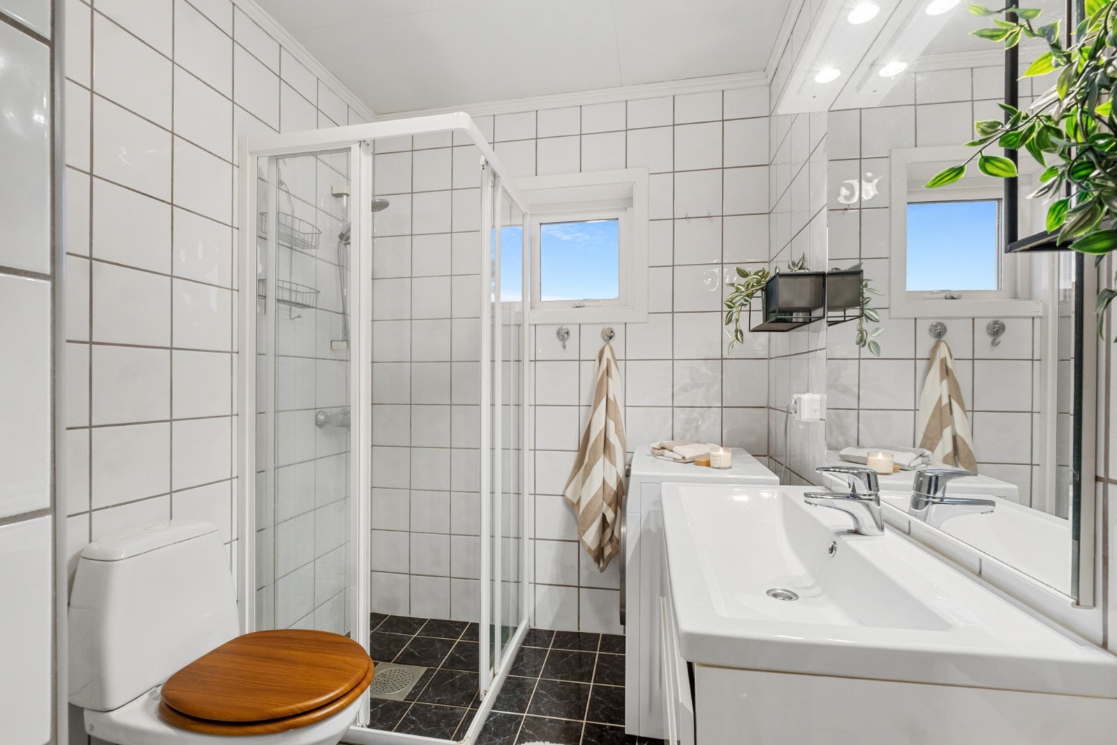 Lyst og tidløst bad med varmekabler i gulv. Dusjvegger og gulvstående toalett. Galleribilde