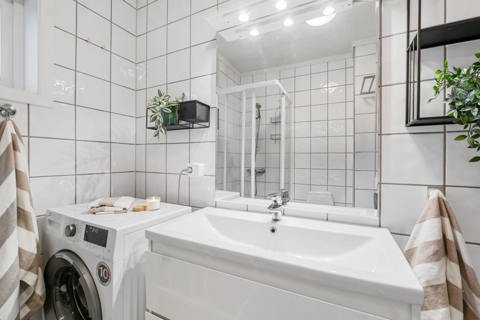 Servantinnredning med speil og lys ovenfor. Opplegg for vaskemaskin. Galleribilde