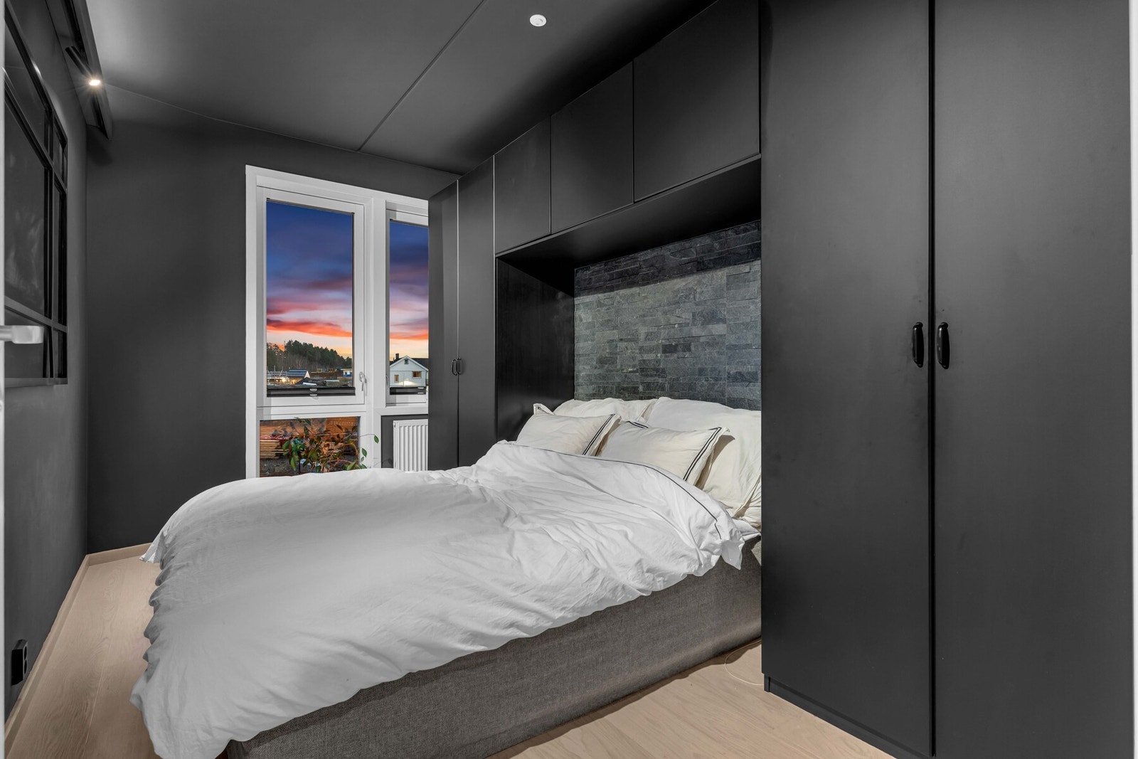 Hovedsoverommet er vel gjennomført med vegger og tak malt i en mørk, elegant fargetone. Plassbygde skap rundt sengen, malt i samme farge, gir rikelig med oppbevaringsplass og et helhetlig uttrykk. Galleribilde