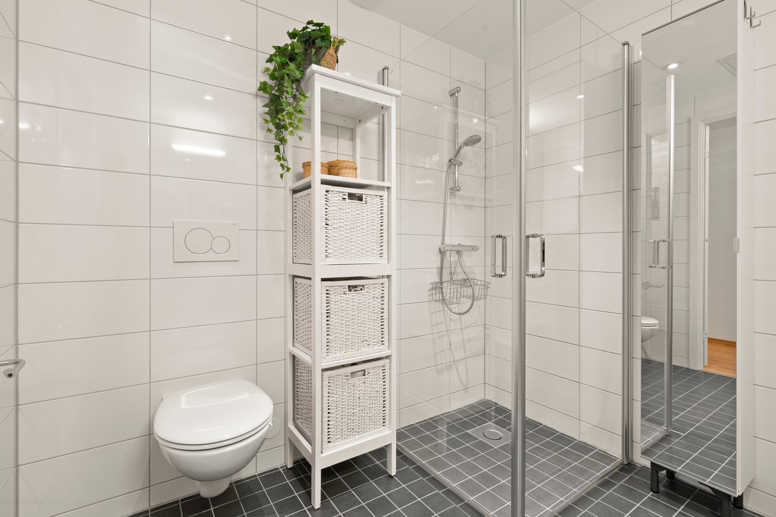 Badet er funksjonelt innredet med vegghengt toalett, dusjnisje, servant og opplegg for vaskemaskin Galleribilde