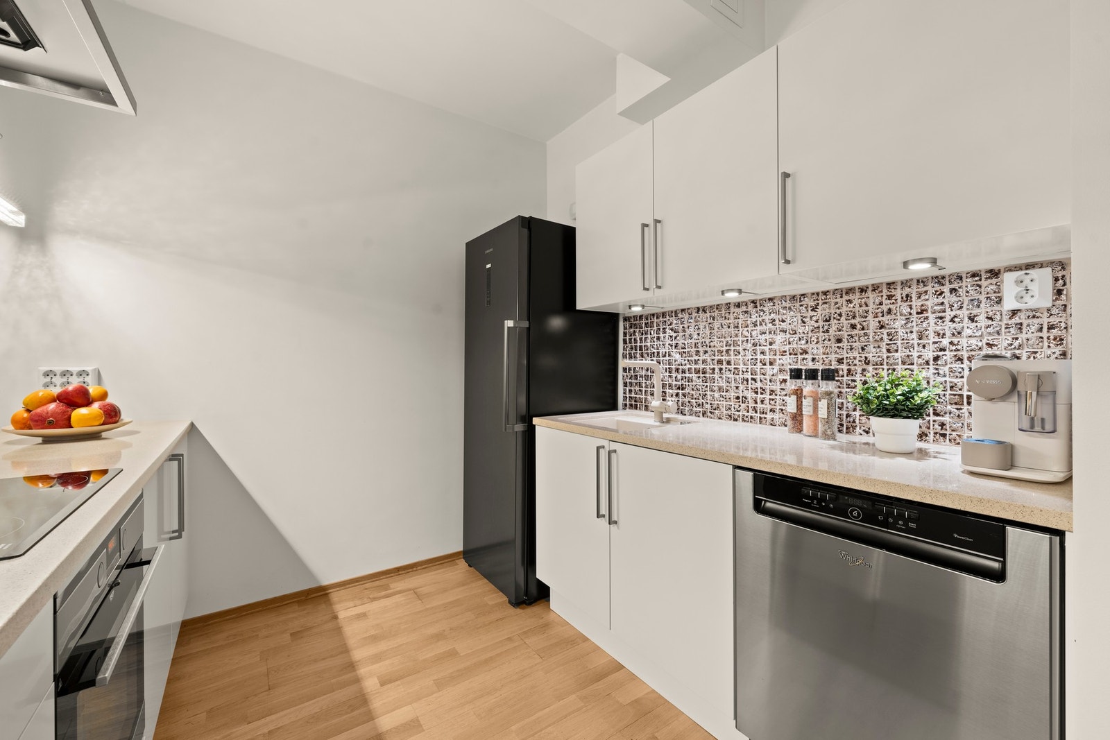 Det er fliser over kjøkkenbenk, og her er det benyttet eksklusive gullbelagte fliser. Det er belysning under overskap og over kjøkkenøy Galleribilde