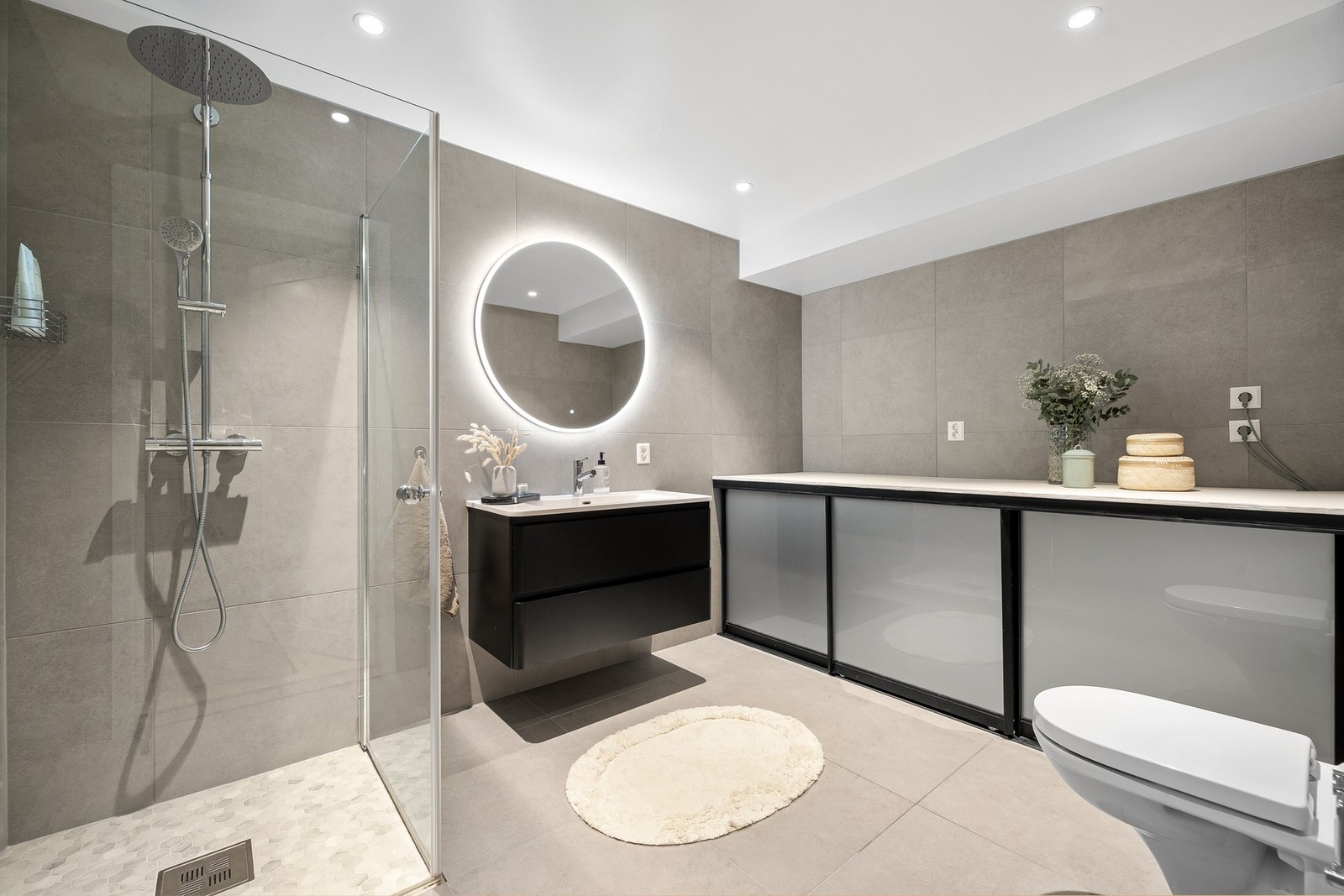 Romslig bad med lekre flis, gulvvarme og en svært praktisk benk med skjult løsning for vaskemaskin. Galleribilde