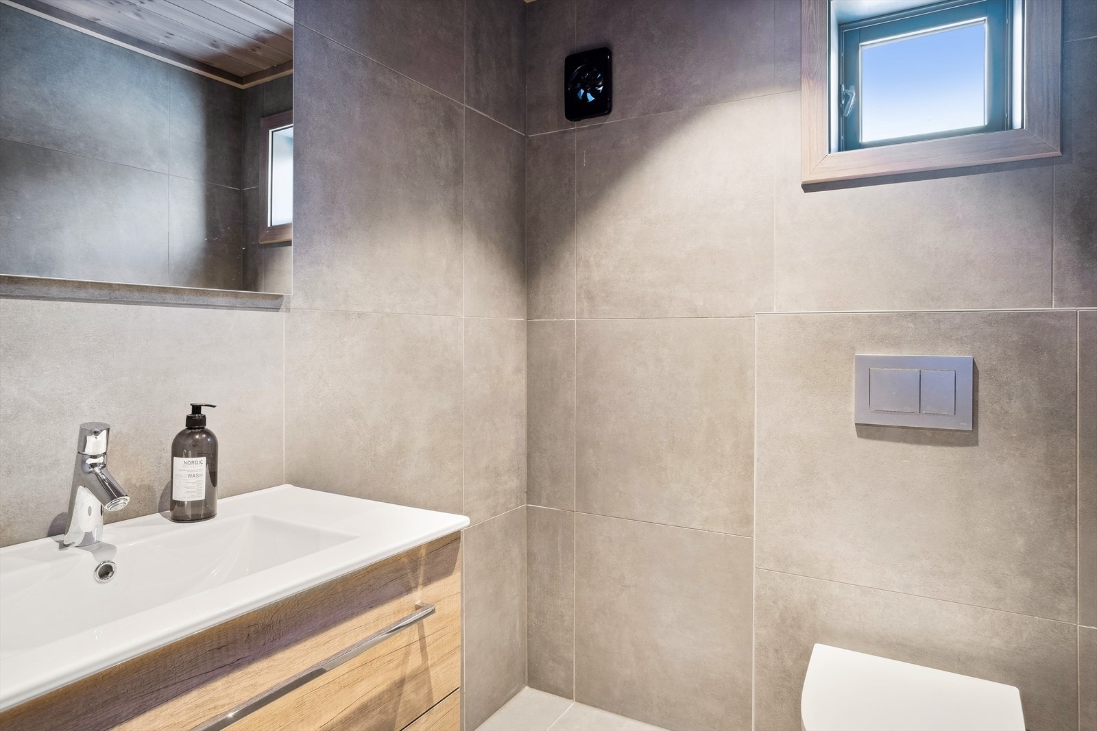 Toalettrom med innredning med servant og veggmontert toalett. Galleribilde