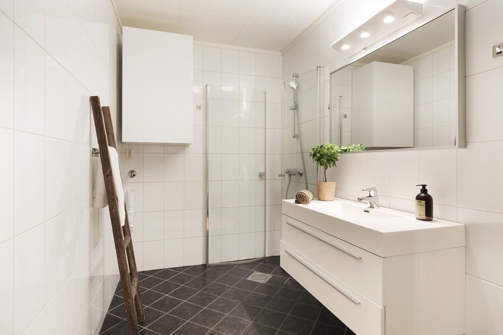 Her er opplegg for vaskemaskin, vegghengt toalett, veggskåp, overskåp ved vaskemaskin, dusjhjørne, servantmøbel med skuffer, støypt vask, spegel og lys. Galleribilde