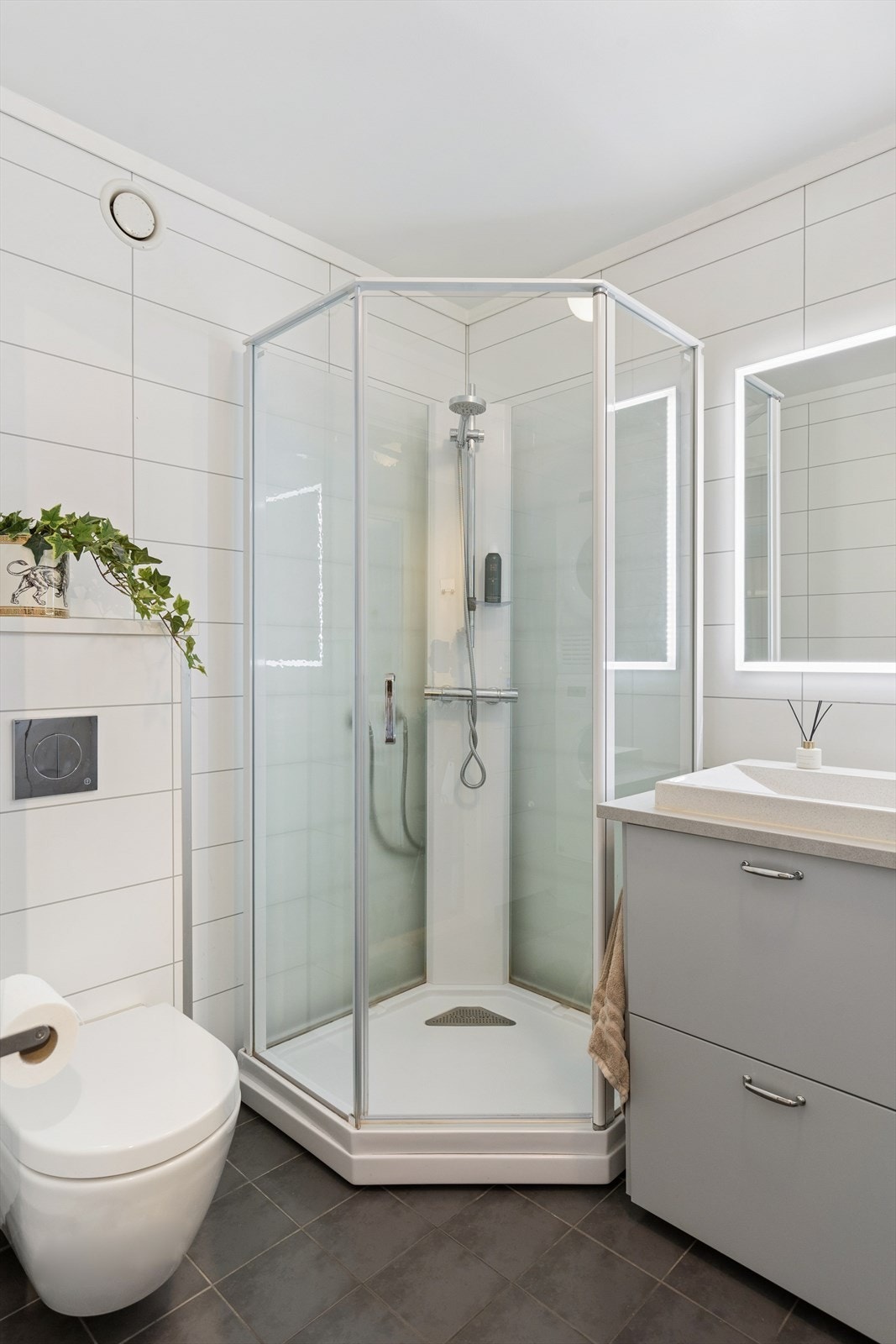 Moderne baderomsløsning med dusjkabinett og vegghengt toalett. Galleribilde