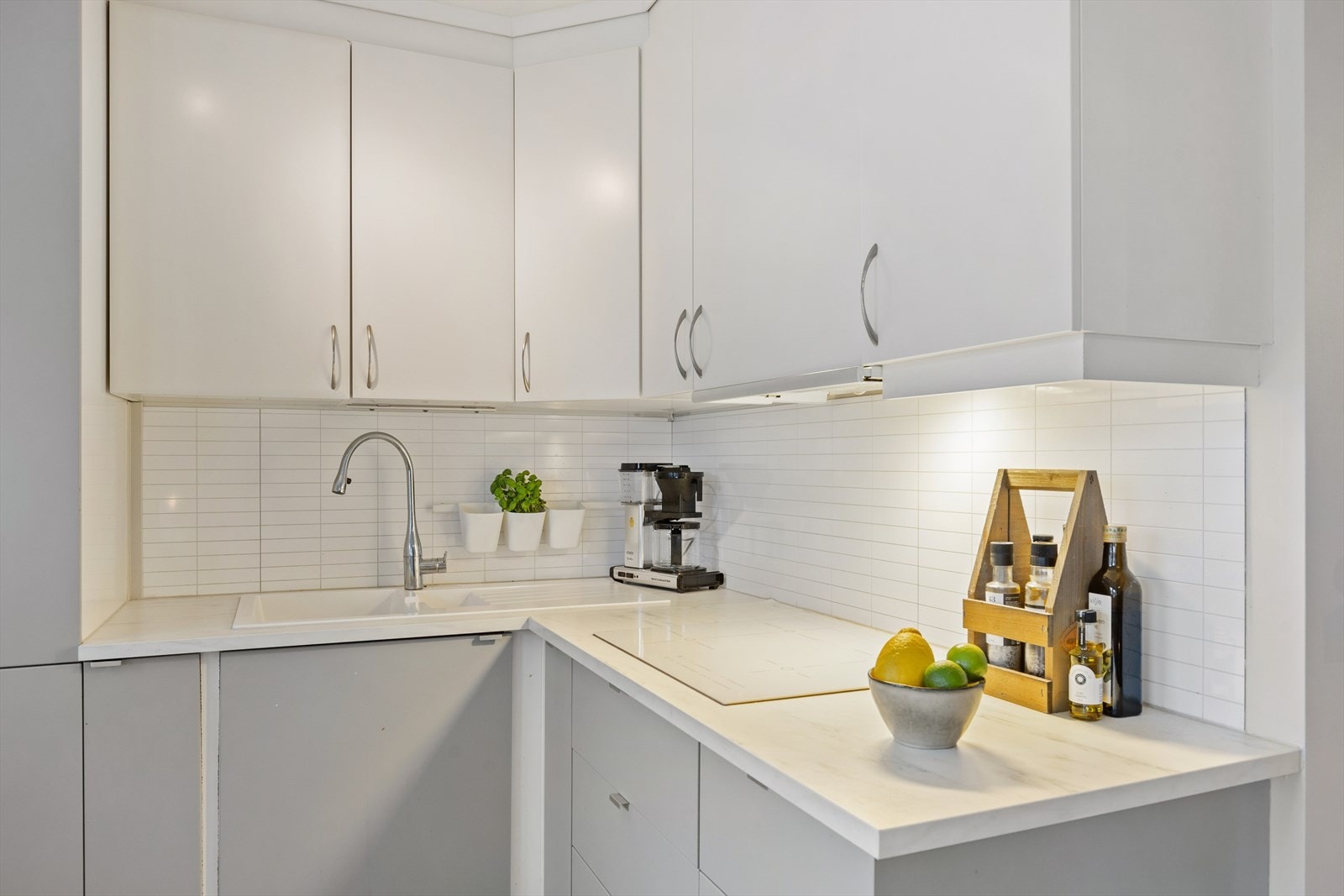 Hvite fliser og innebygd belysning gir en ryddig arbeidsflate. Galleribilde