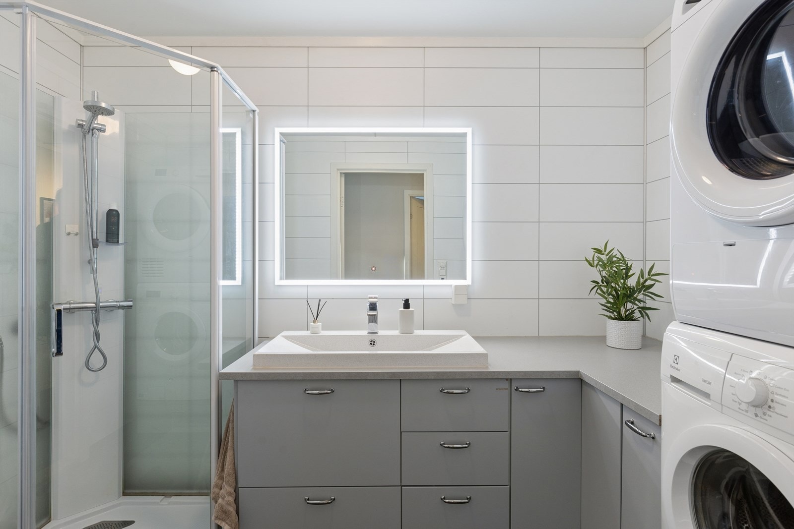 Badet fra 2010 er et kombinert baderom og vaskerom med flislagt gulv med elektriske varmekabler og baderomsplater på veggene. Galleribilde