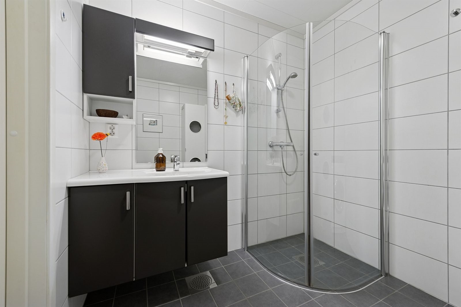 Moderne, helfliset bad med servantinnredning, gulvmontert toalett og dusjhjørne med glassdører. Galleribilde