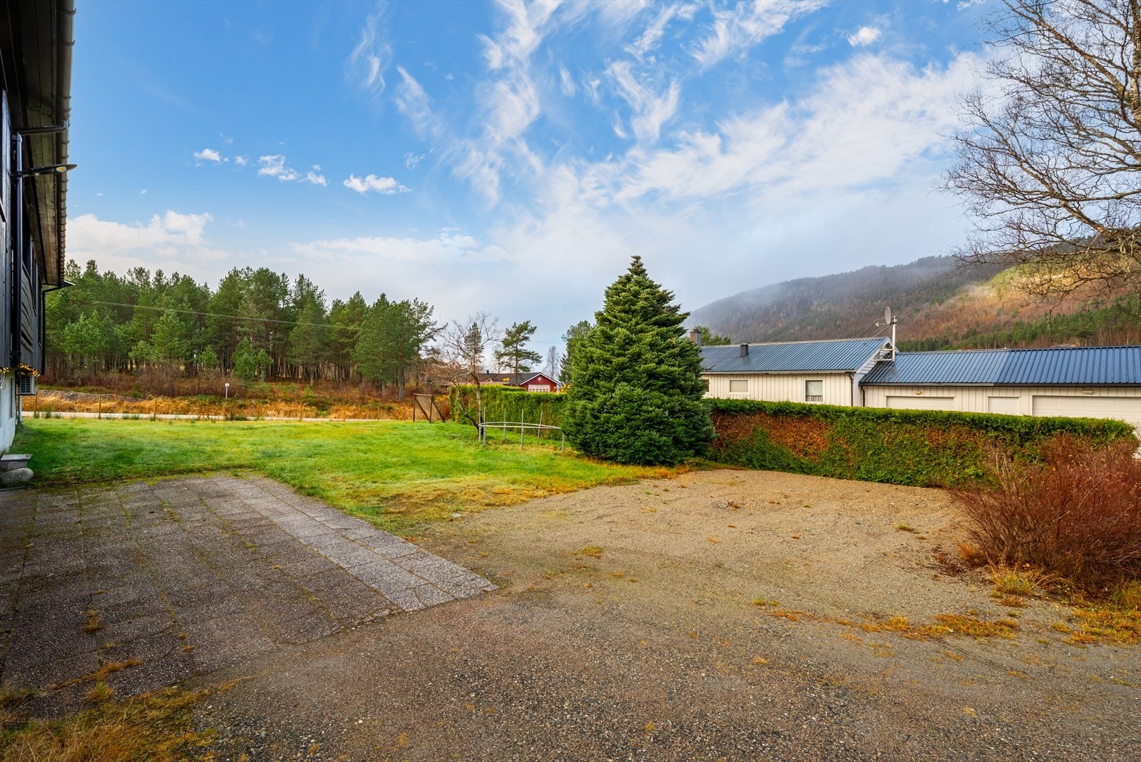 Tomta består av to gårds- og bruksnummer med et samlet areal på ca. 1 mål. Flat tomt som er beplantet med plen, busker, hekk, trær og gjerde. Betongheller i innkjørsel. Galleribilde