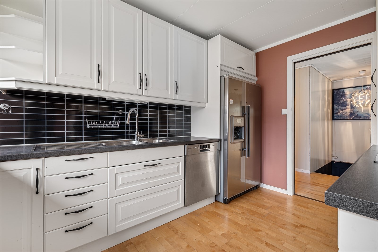 Lys og stilren innredning med god oppbevaringsplass i over- og underskap. Nedfelt induksjonstopp, kjøl/fryseskap, oppvaskmaskin og integrert stekeovn medfølger i handelen. Galleribilde