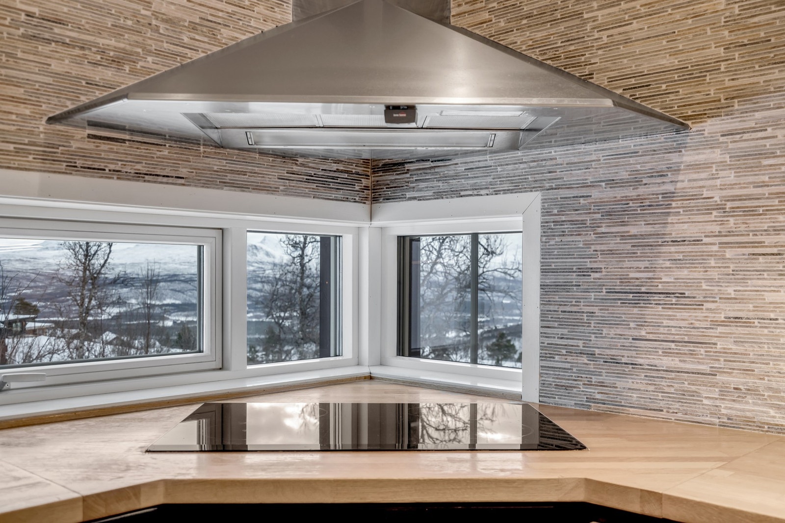 Smart hjørneløsning med kjøkkenvindu, ventilator og steketopp - en praktisk og stilren detalj som gir både lys og funksjonalitet Galleribilde