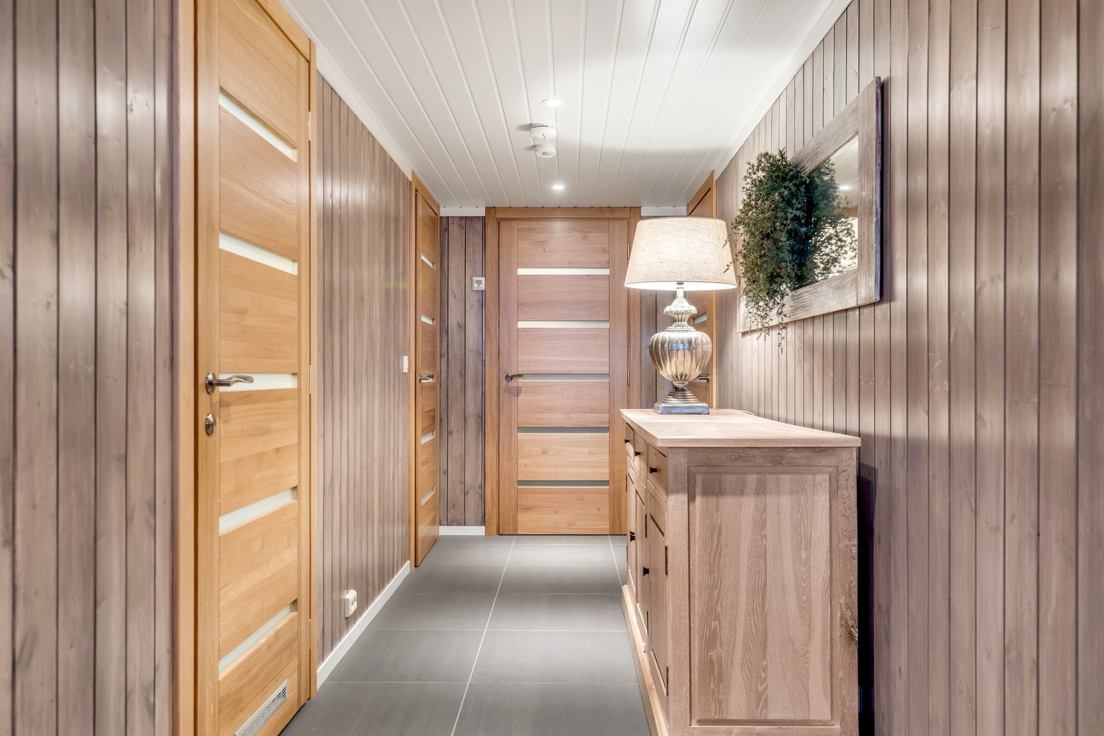 Innbydende gang med flislagt gulv og eksklusive dører som setter et elegant preg på rommet Galleribilde