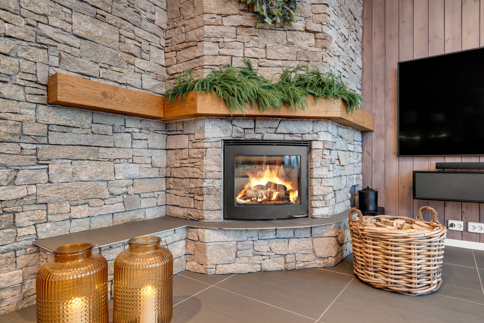 Koselig vedfyring med peisinnsats, omkranset av vakker skiferstein - gir varme og stemning til stuen Galleribilde